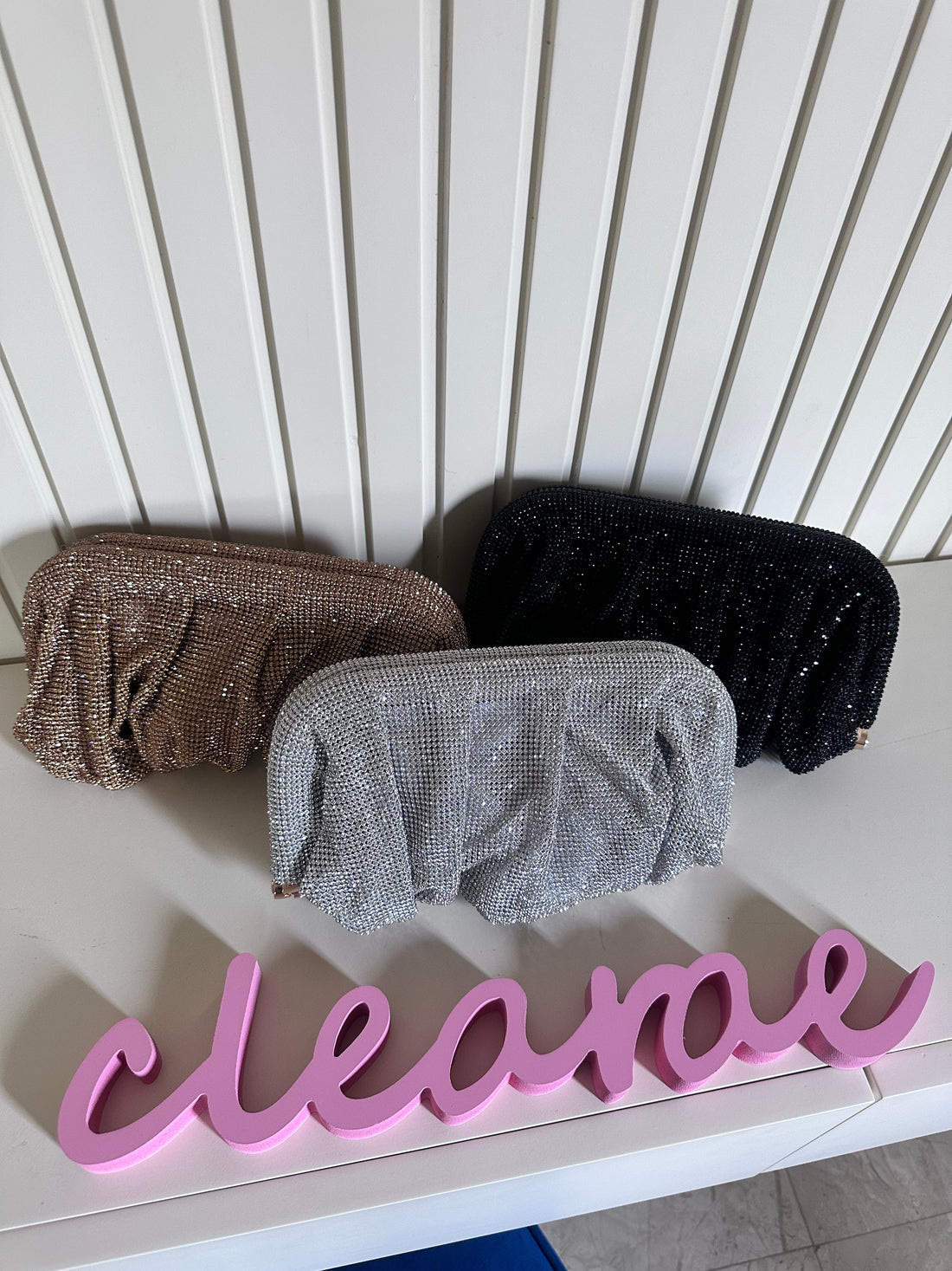 Three glittery pouches in brown, gray, and black on a white surface with 'cleanae' in pink letters.
