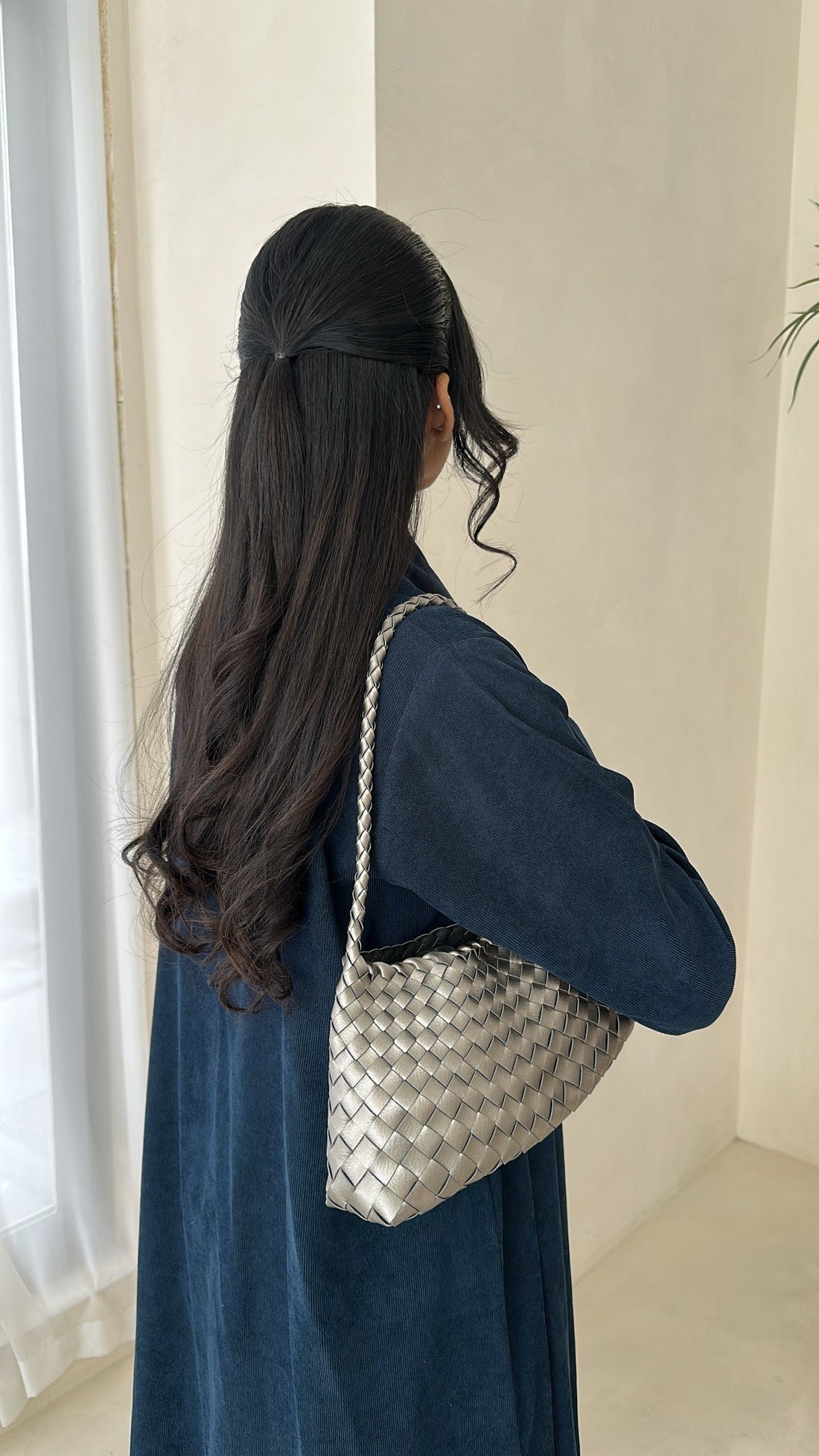 Woman holding a woven handbag in a minimal indoor setting