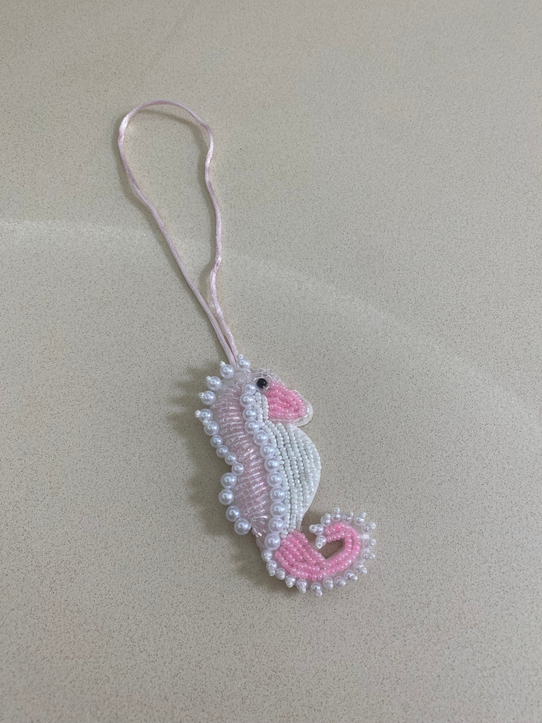 Beaded seahorse charm on a beige background
