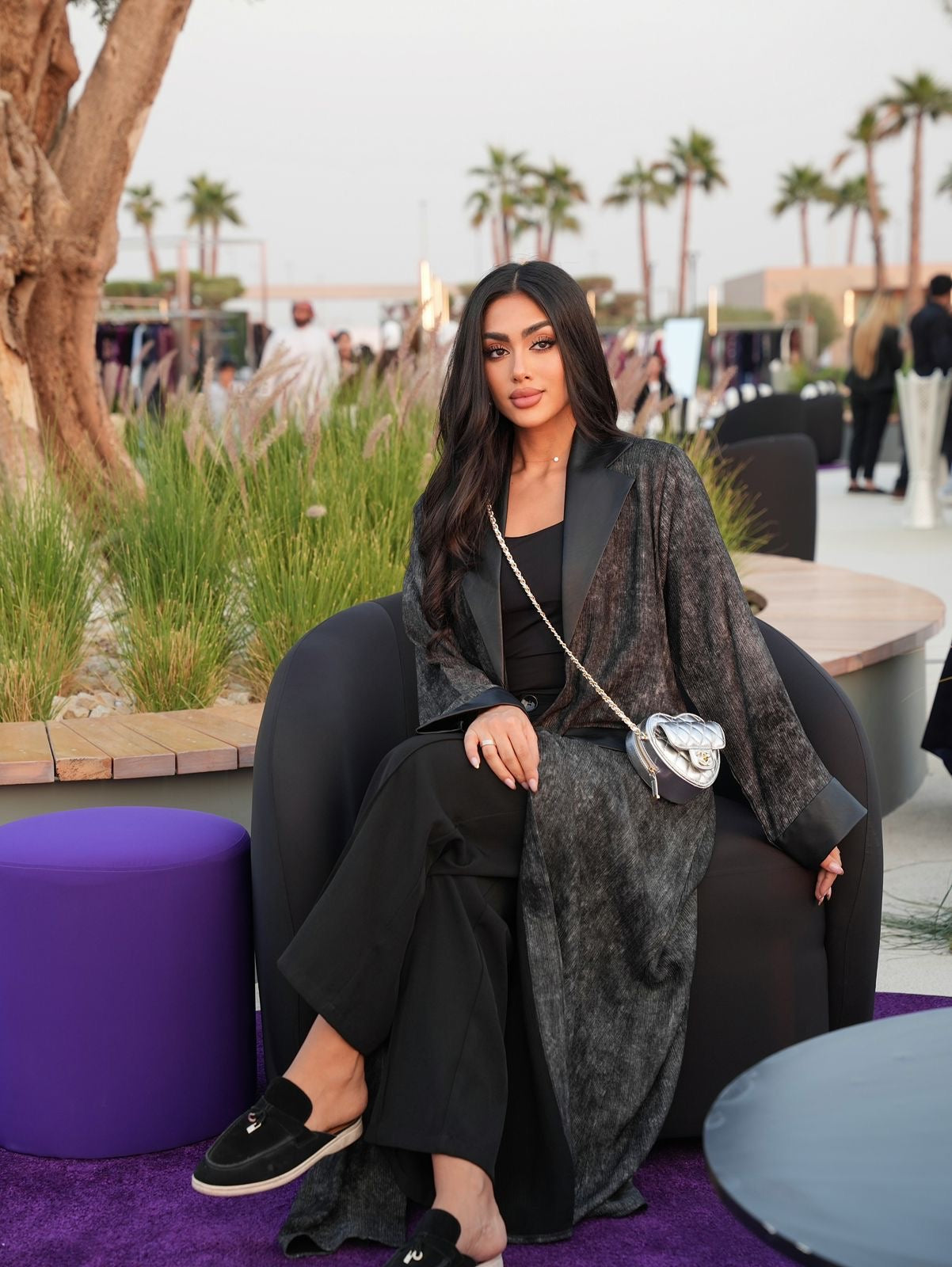 Woman sitting on a chair with palm trees and people in the background