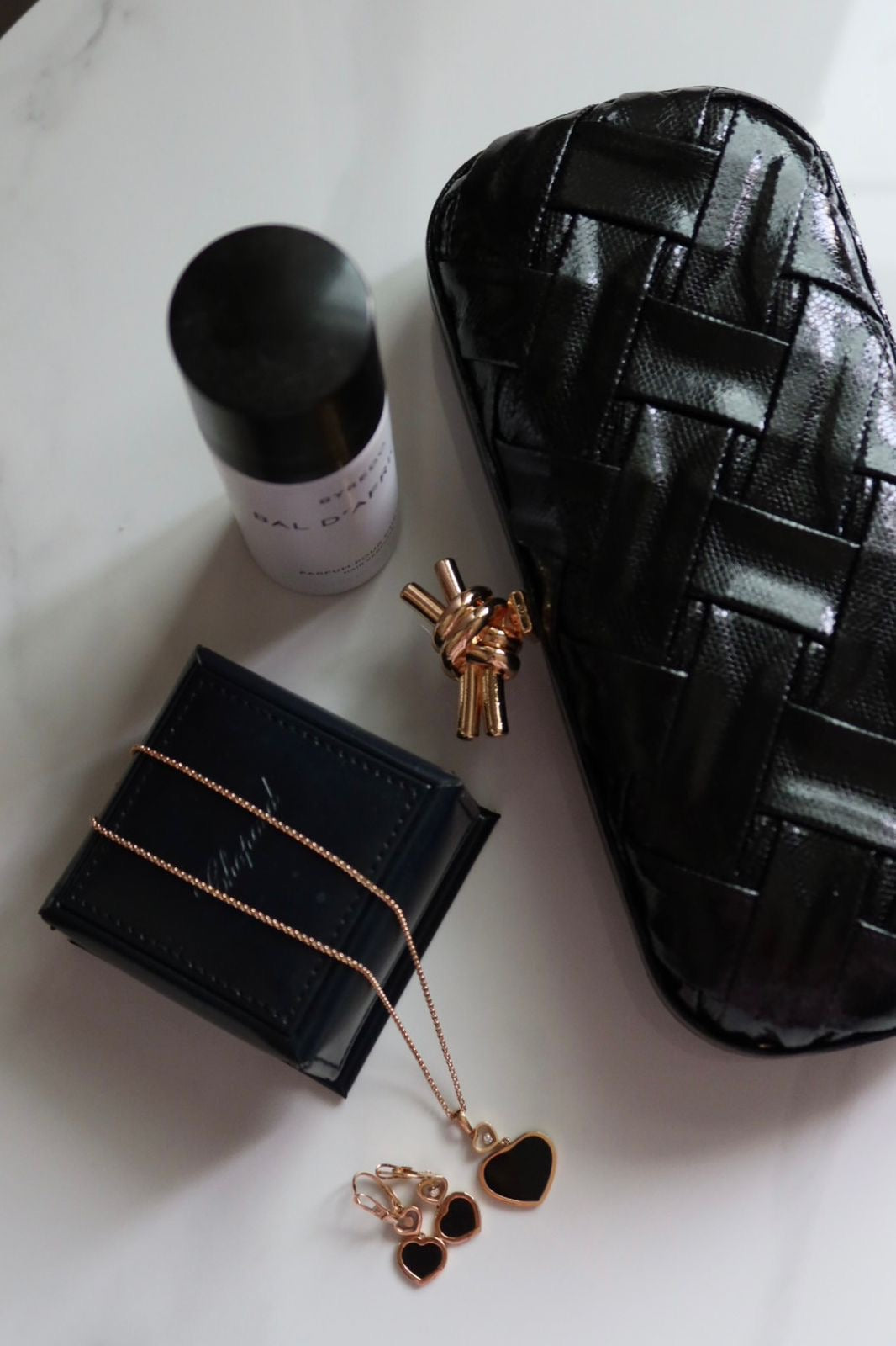 Black jewelry box, necklace, earrings, and black container on a white surface