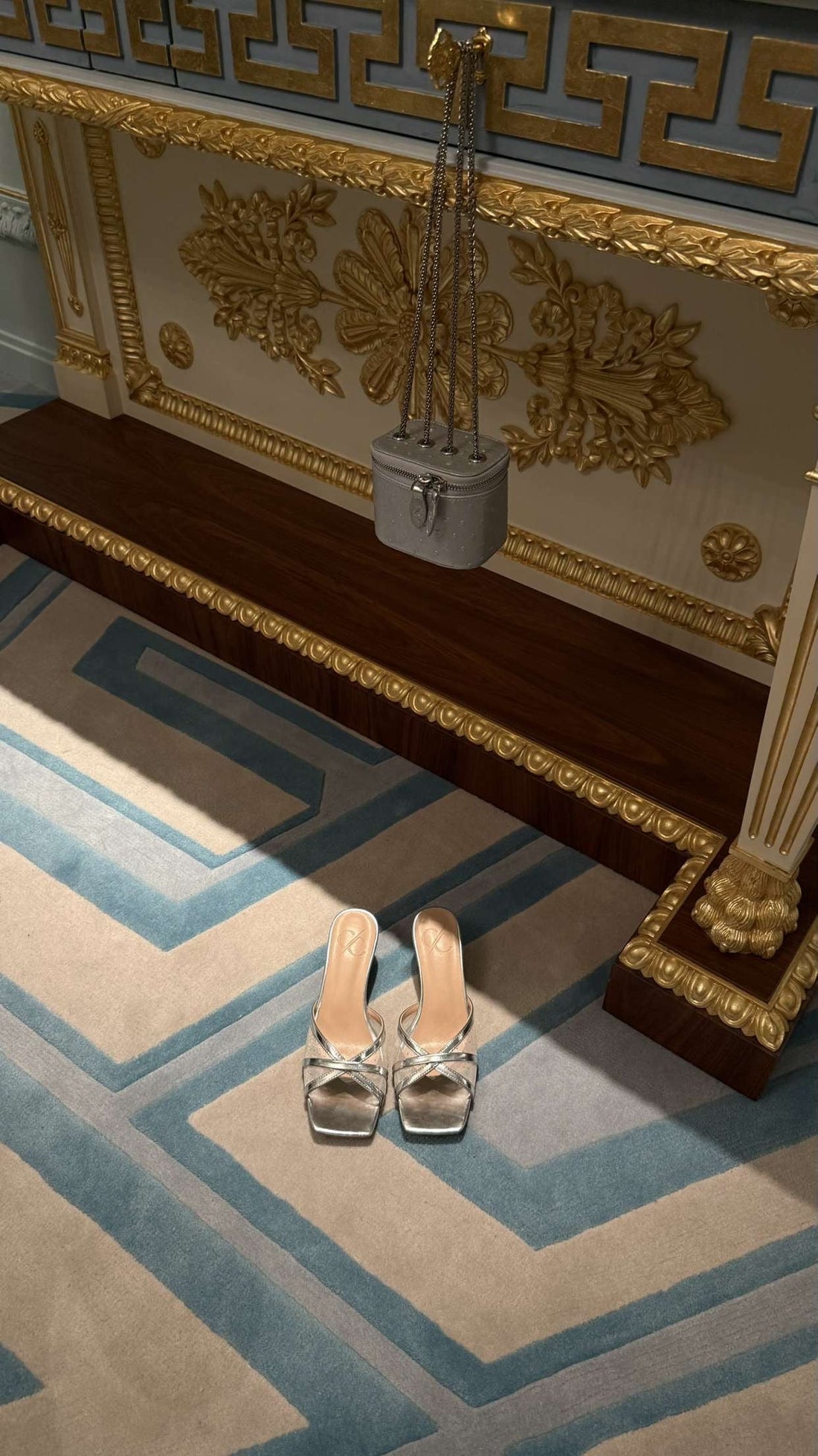 Decorative shoe rack with gold accents on a patterned rug