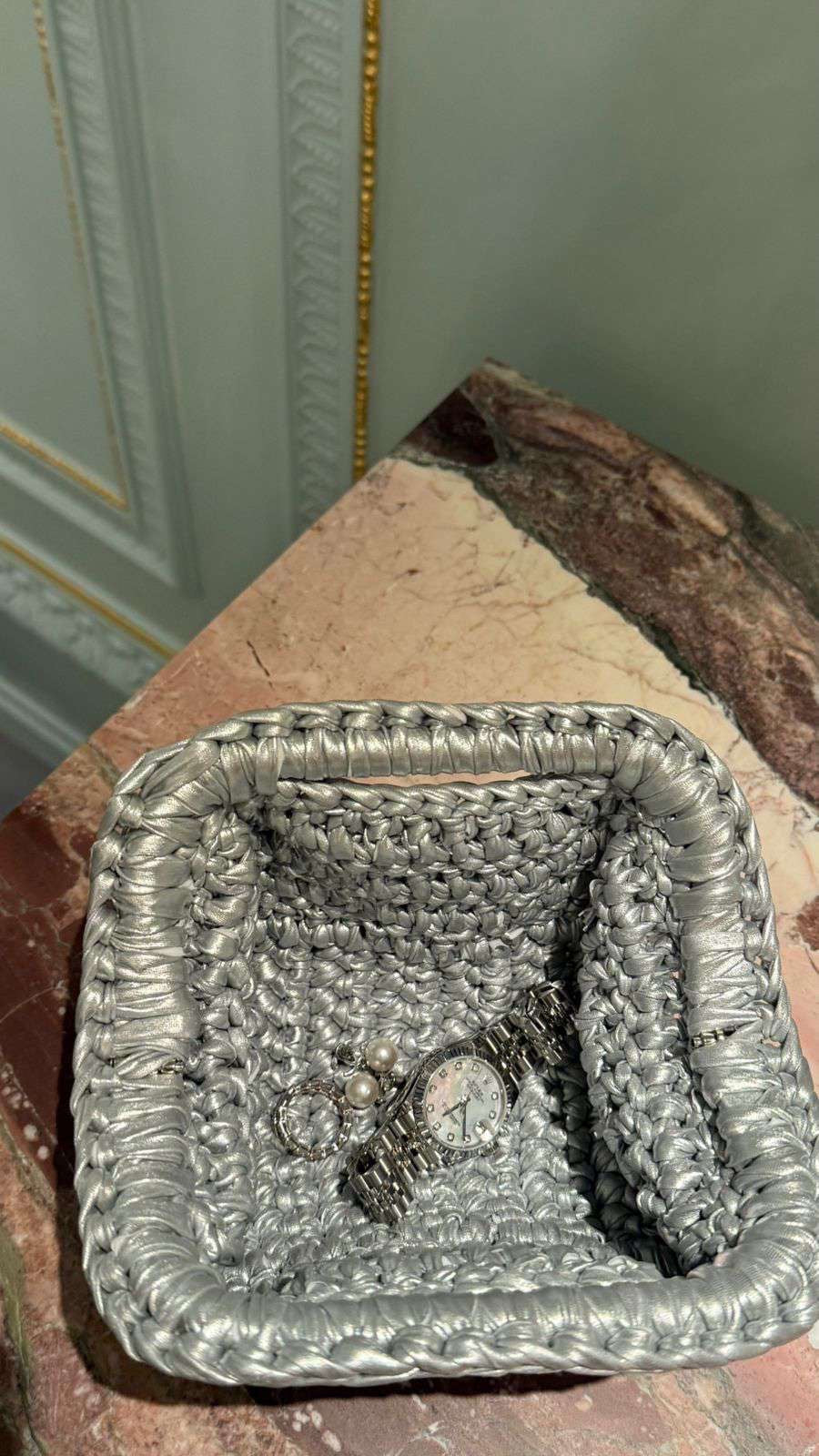 Decorative silver tray with jewelry on a textured surface