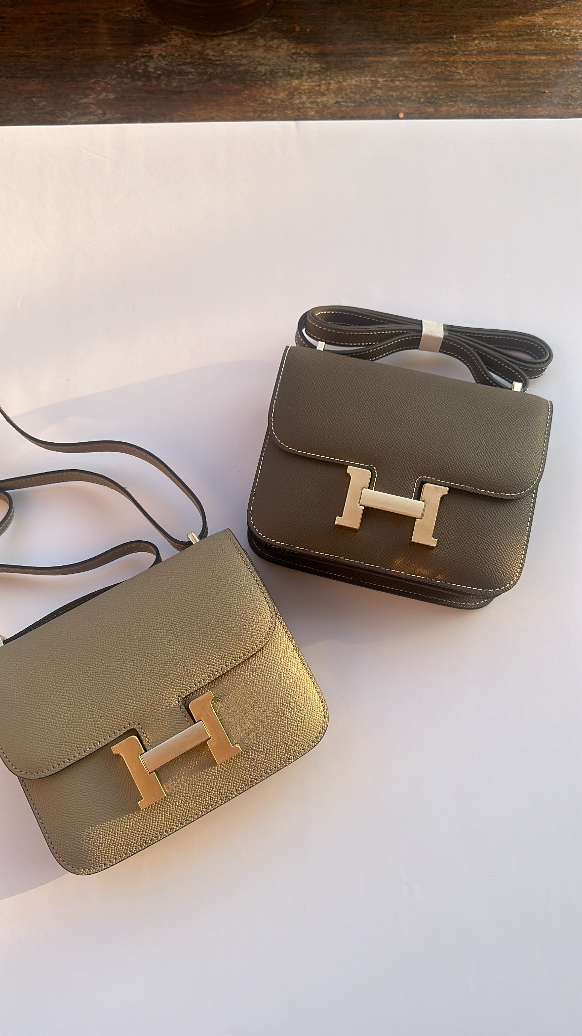 Two green handbags with gold 'H' logos on a white background