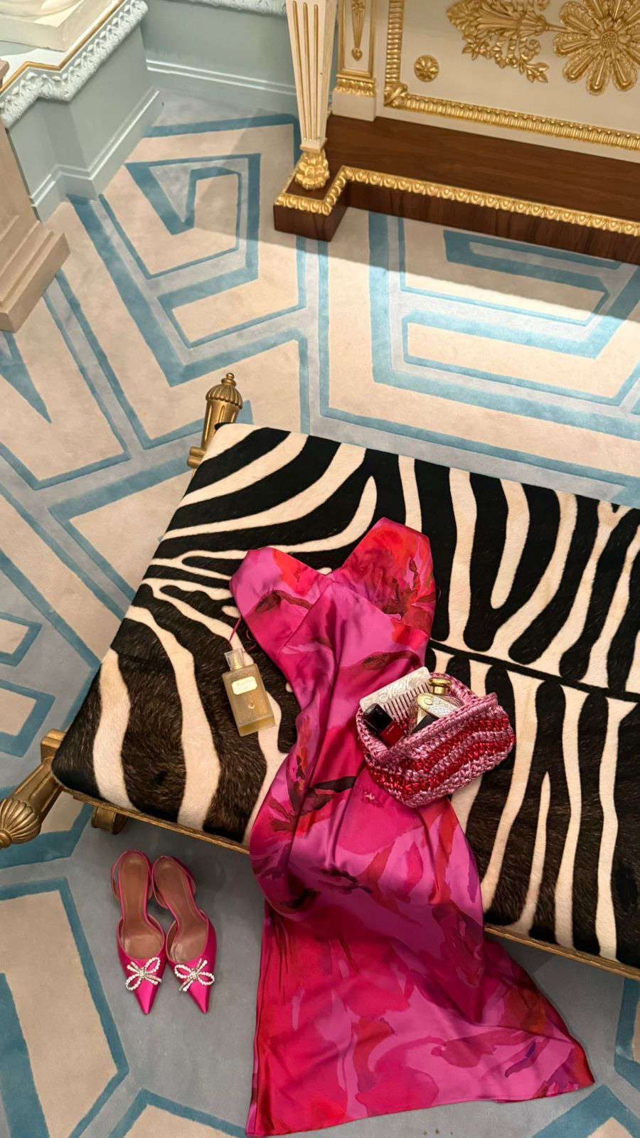 Zebra-patterned bench with pink dress and shoes on a geometrically patterned floor.