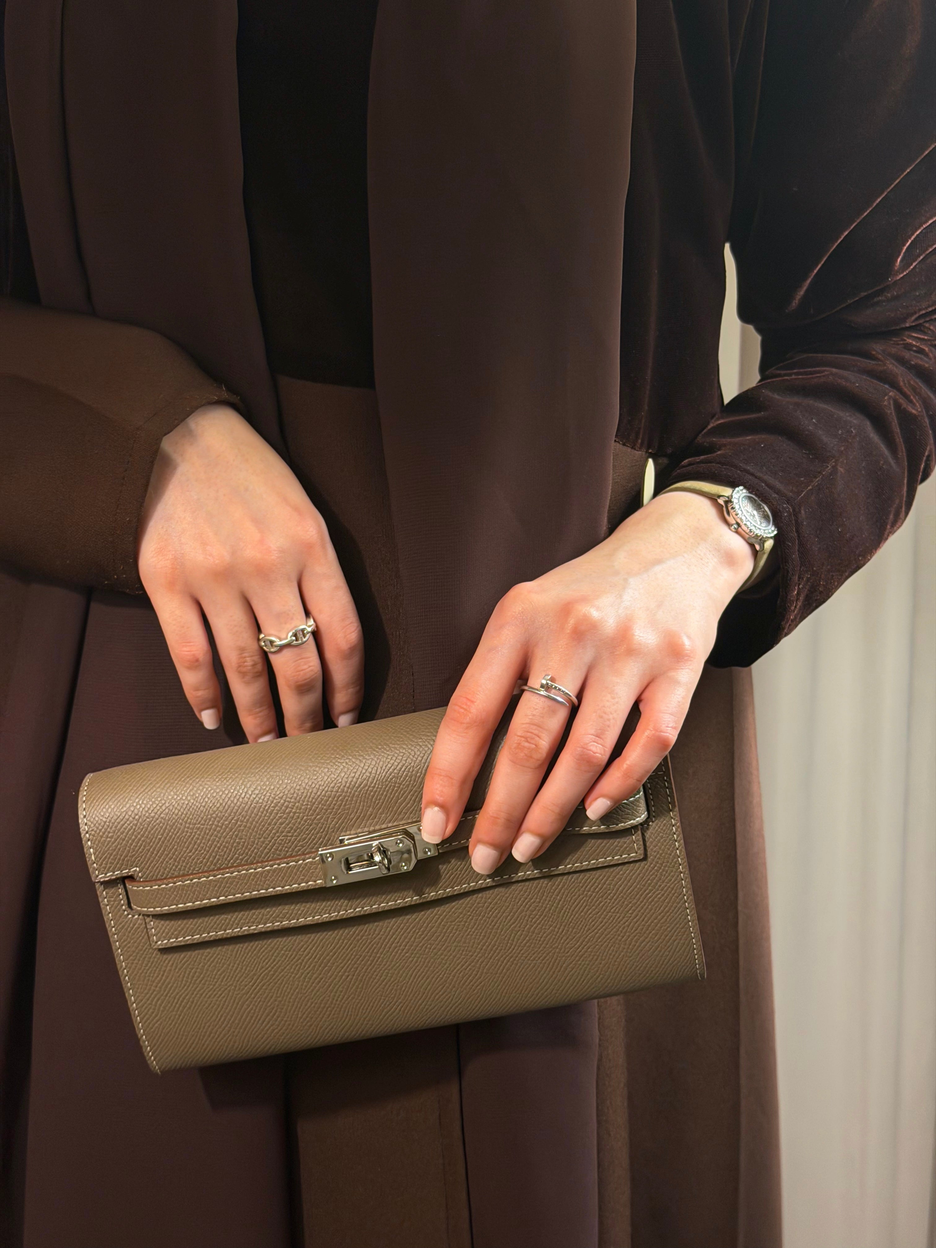 Person holding a green clutch with a neutral background
