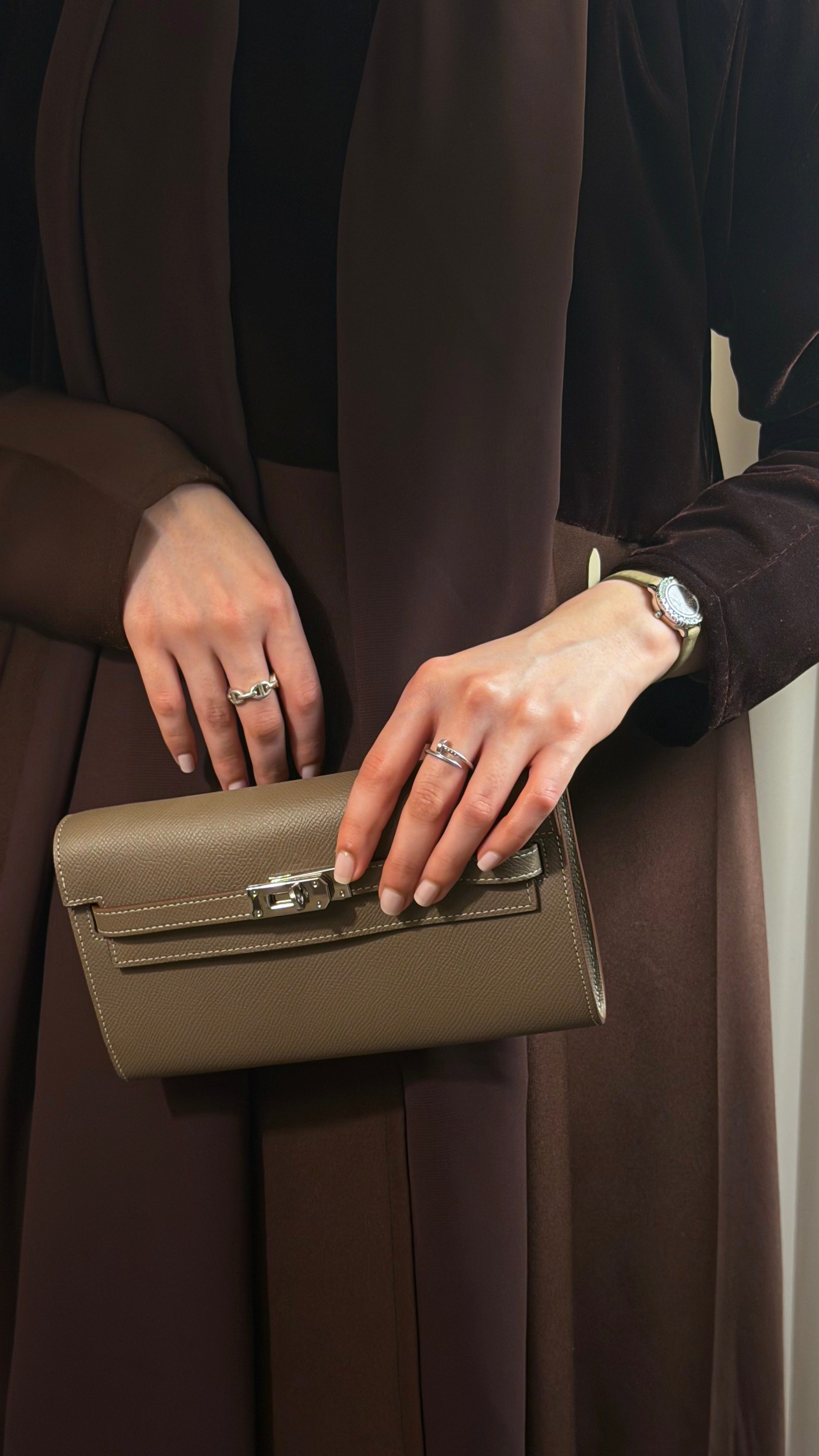 Person holding a green handbag with a neutral background
