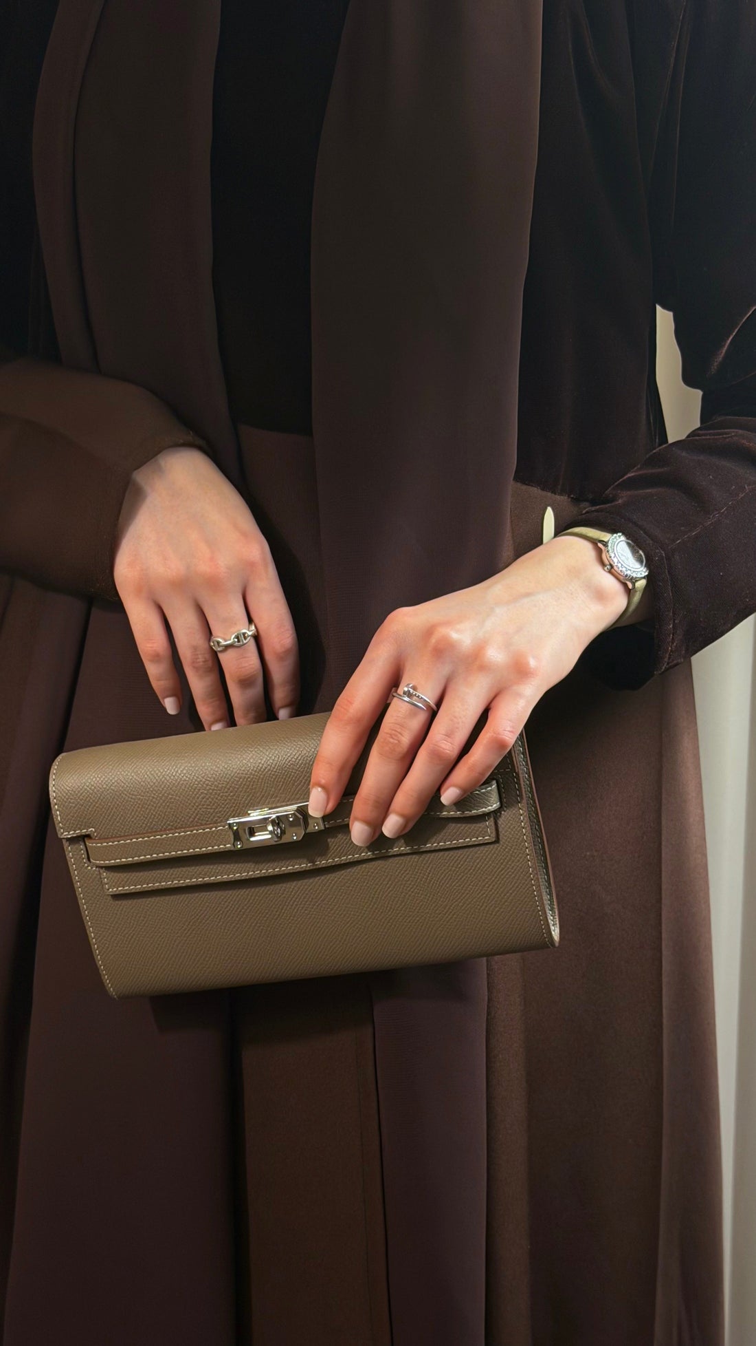 Person holding a green handbag with a neutral background