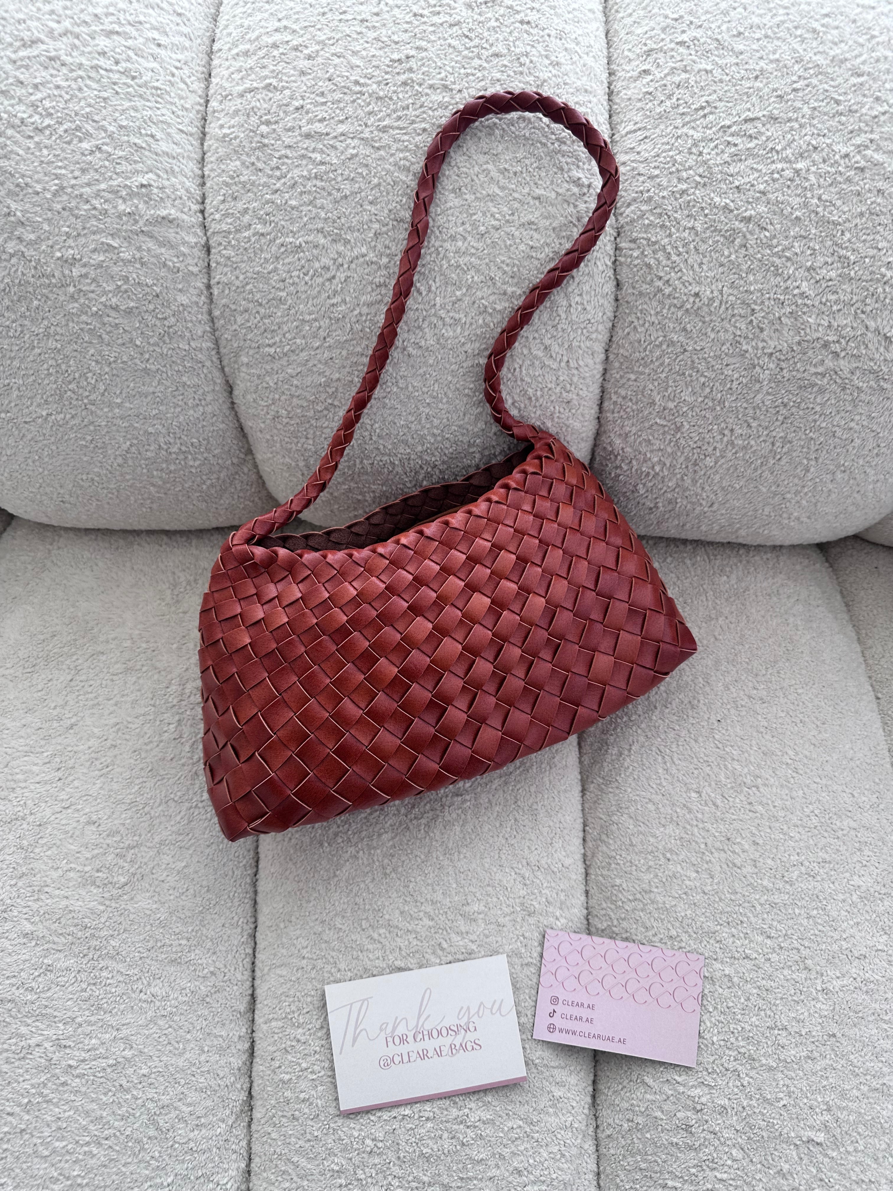 Red woven handbag on a light gray couch with business cards below.