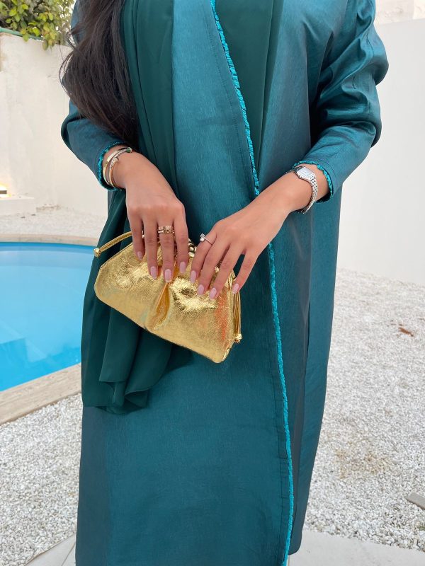 A person holding a gold-colored, medium-sized handbag.