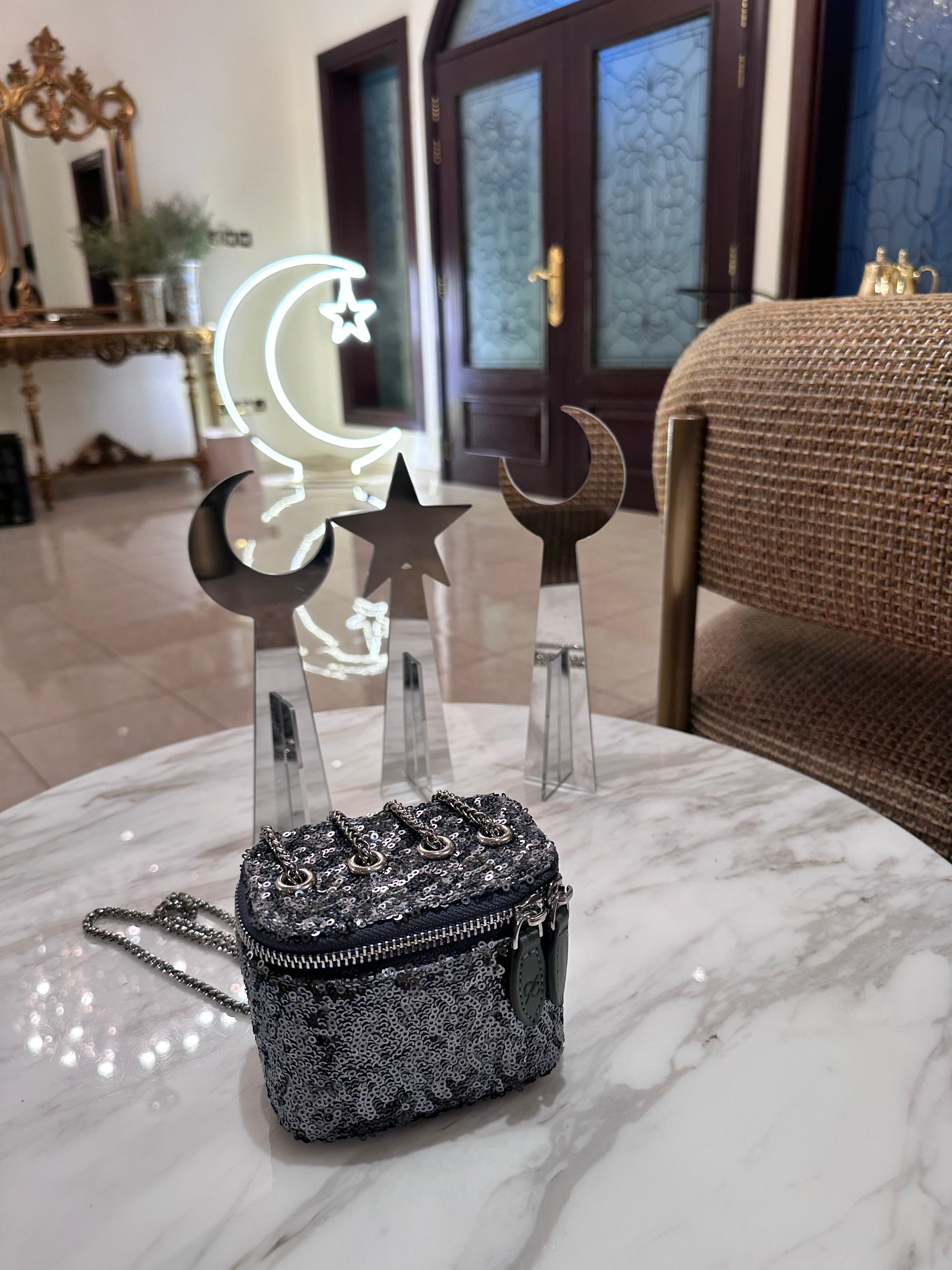 Black lace handbag on a marble surface with decorative moon and star stands in the background.