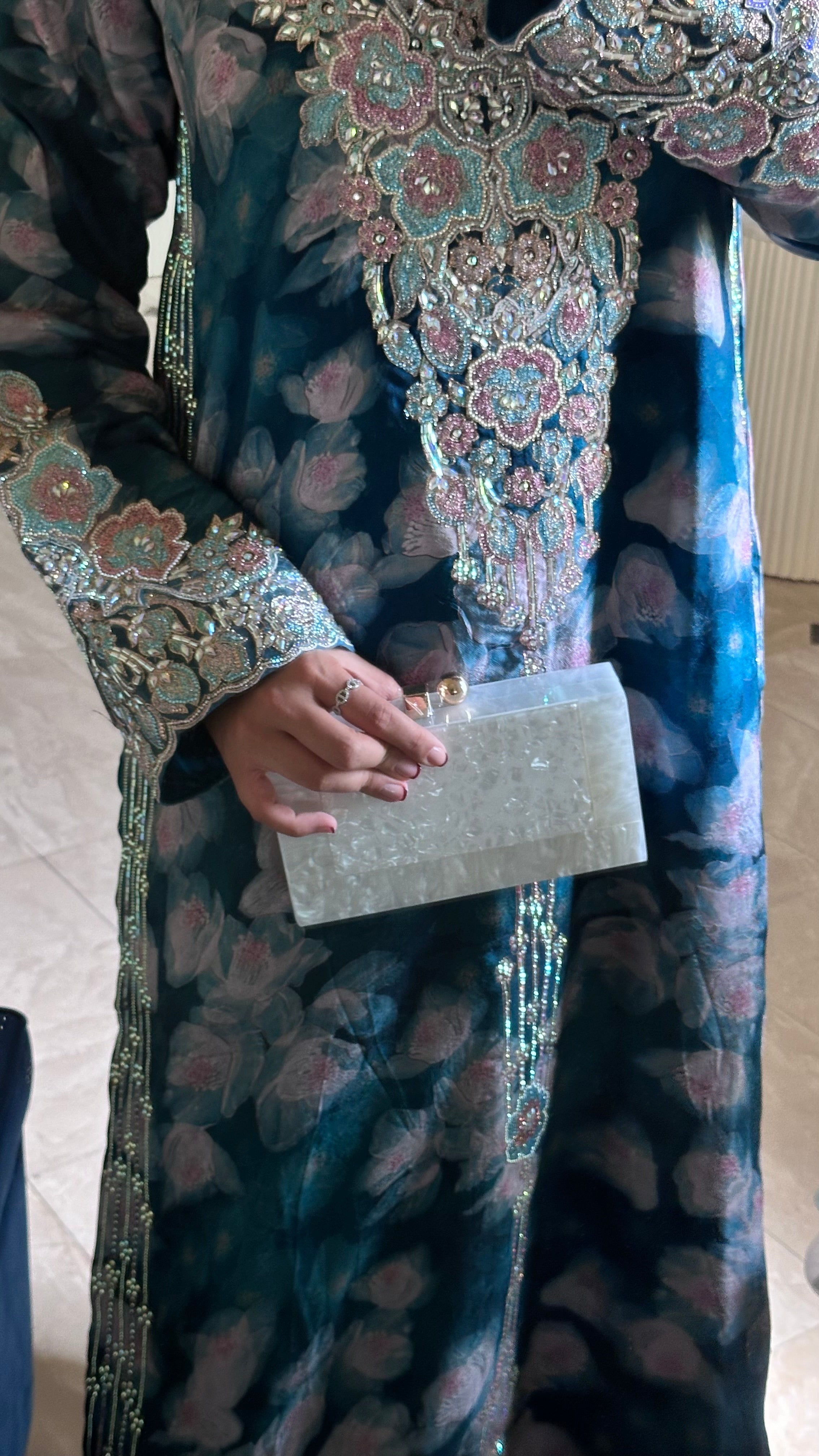 Person wearing a detailed traditional outfit with a clutch