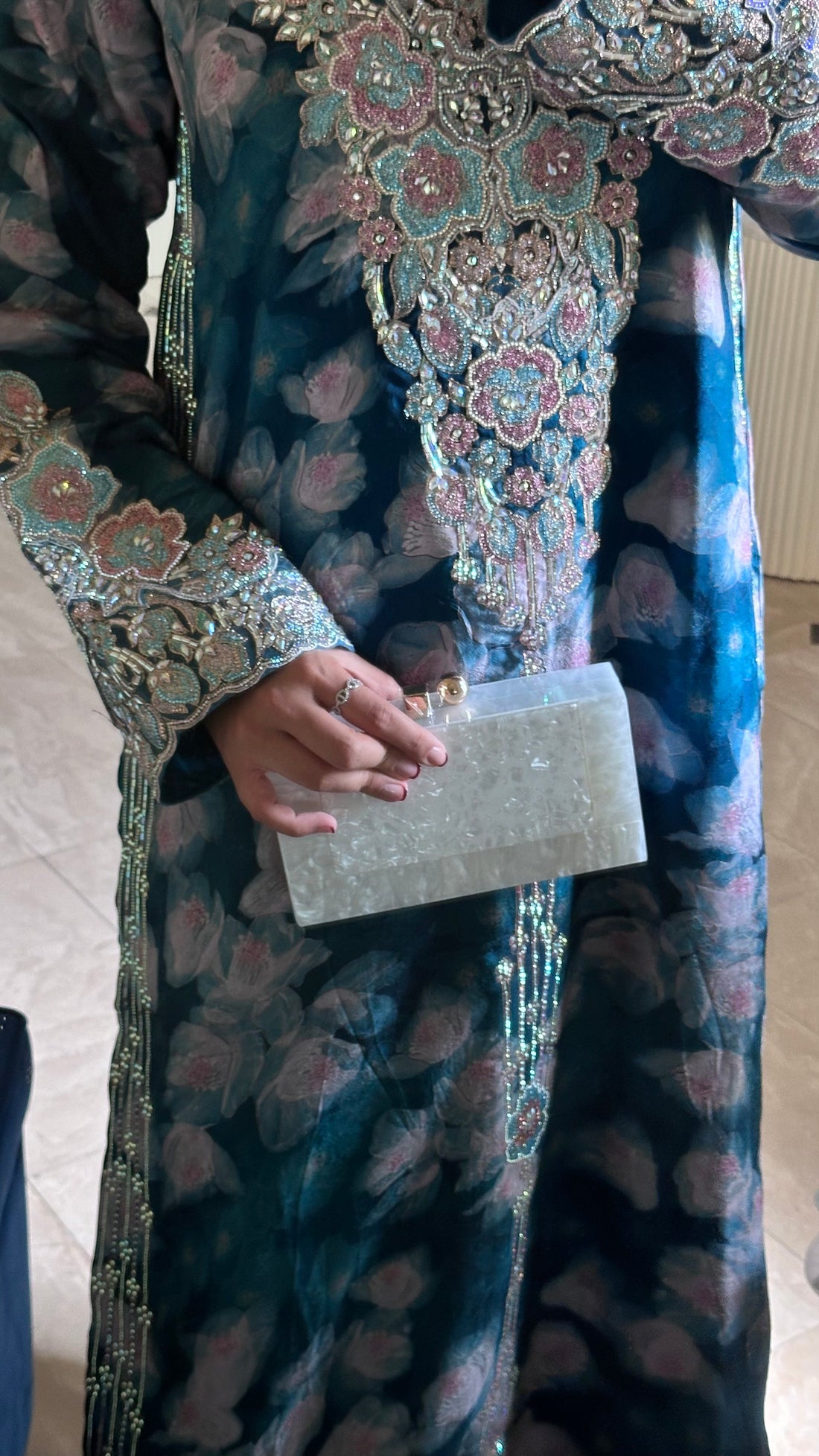 Person wearing a detailed traditional outfit with a clutch