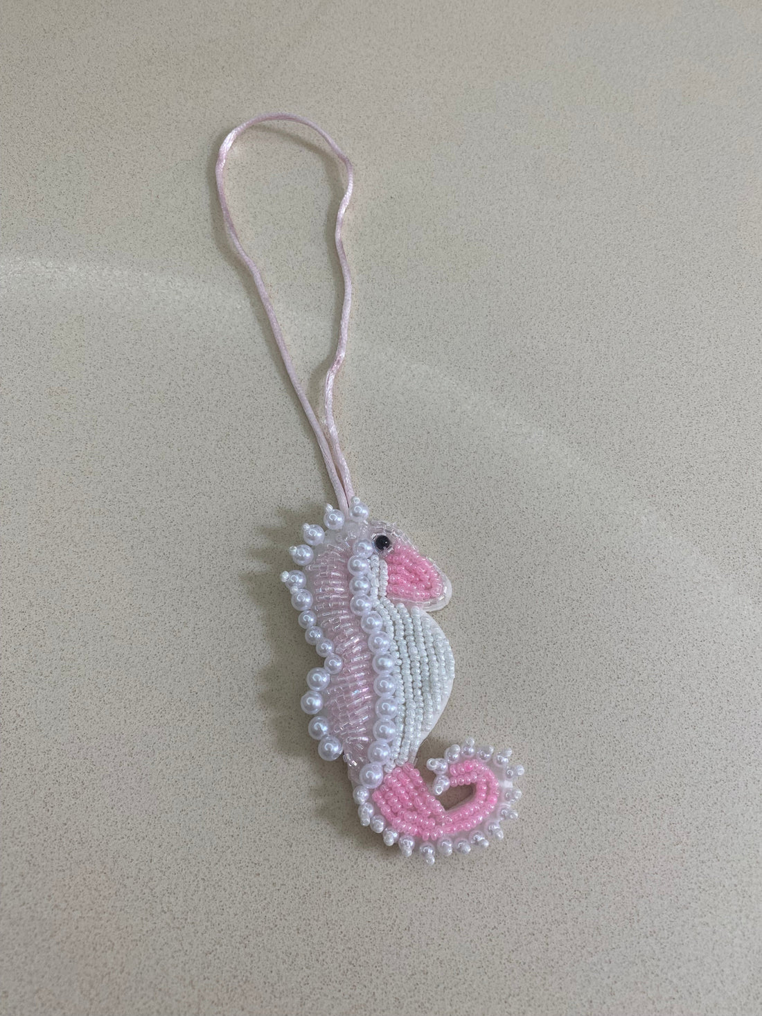 Beaded seahorse charm on a beige background