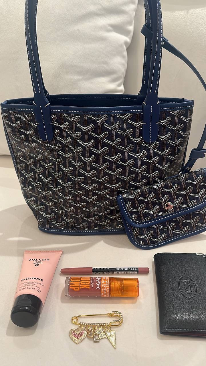 Blue patterned handbag with cosmetic items on a white surface