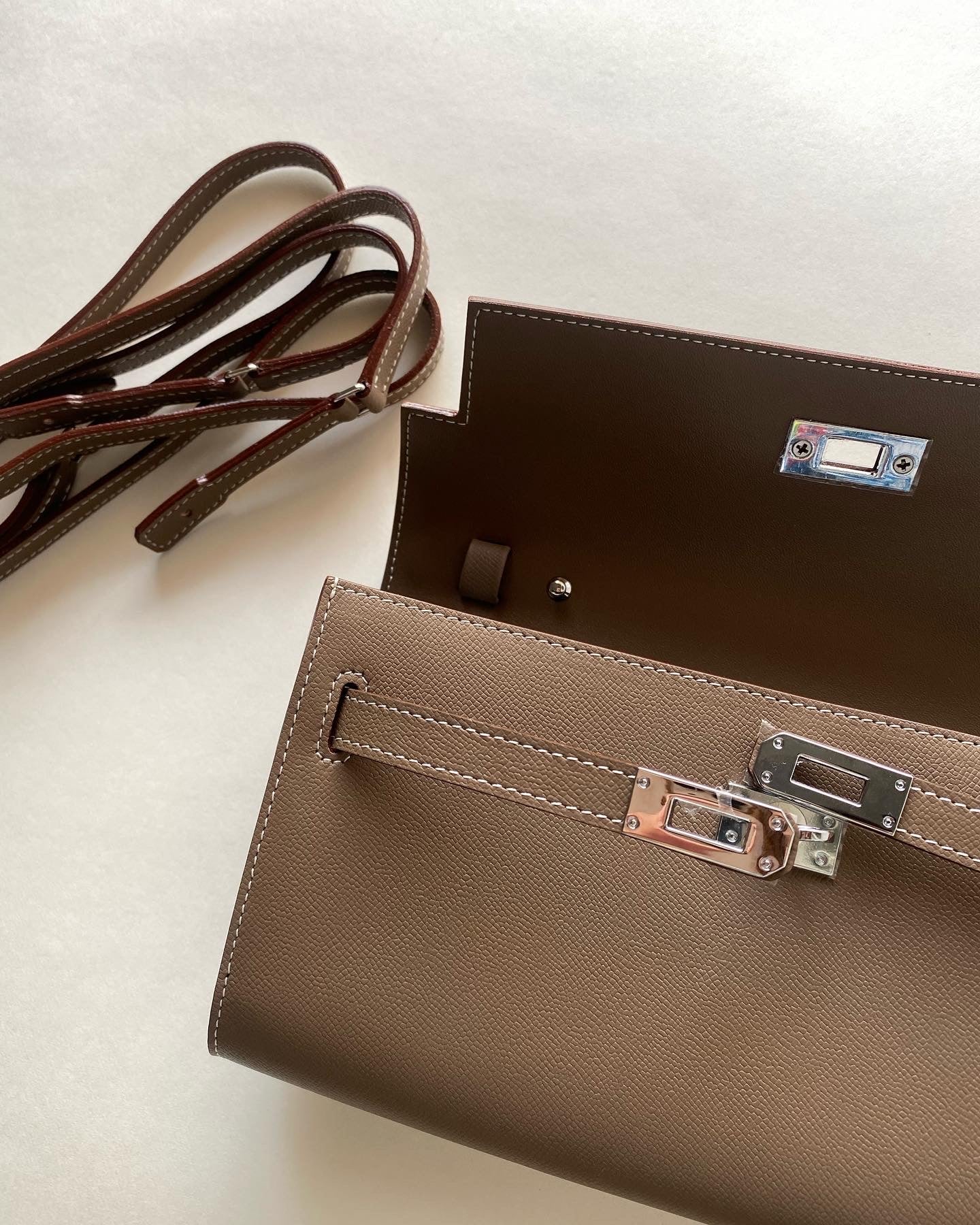 Brown leather handbag with silver clasp on a light beige background