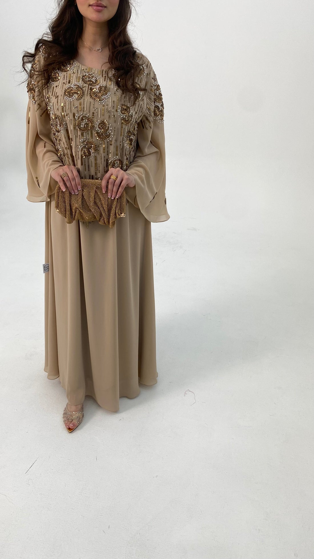 Woman wearing a beige dress with floral embroidery on a white background
