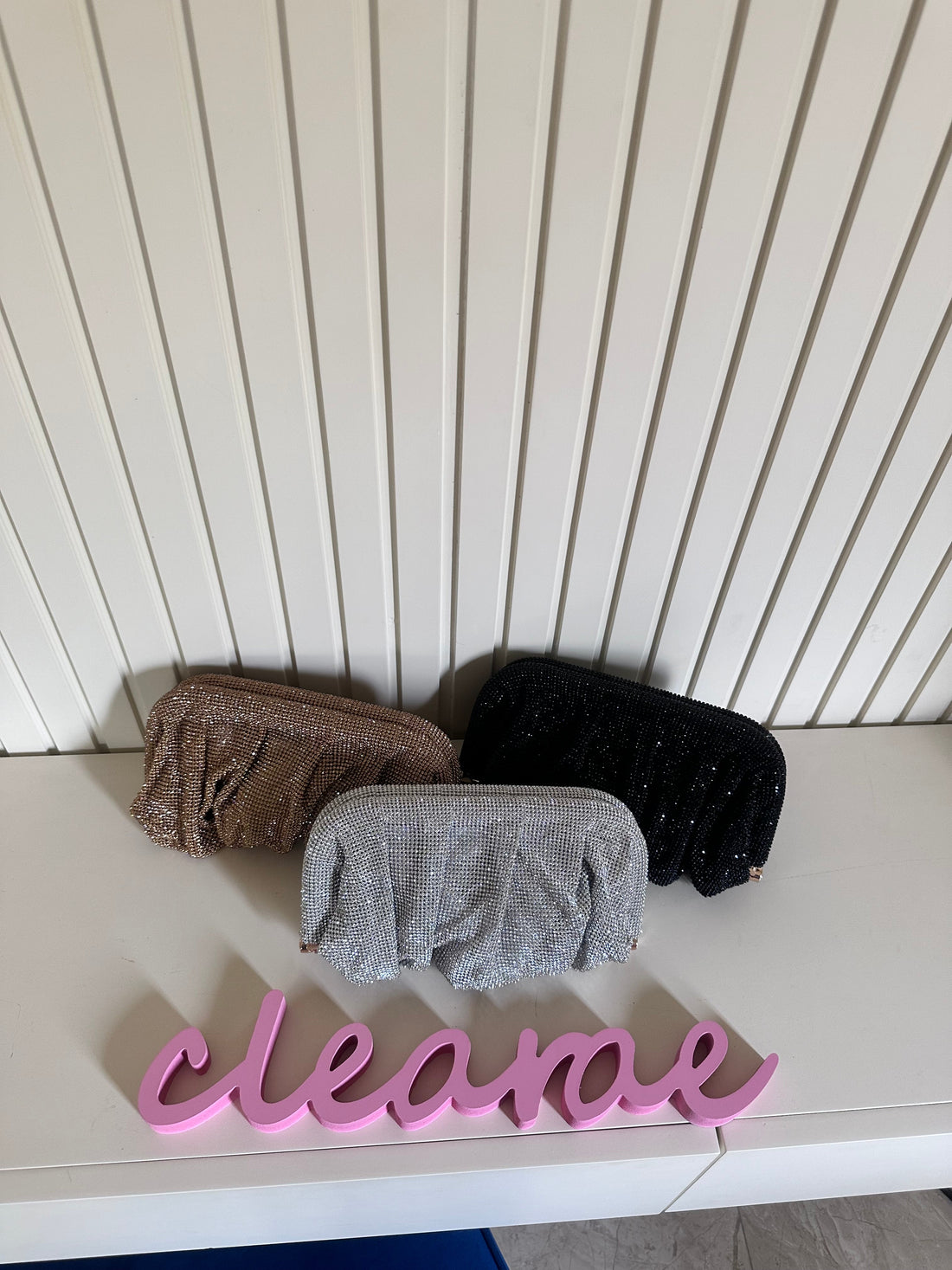 Three sponges on a white surface with a 'clean' sign in front of a white paneled wall.