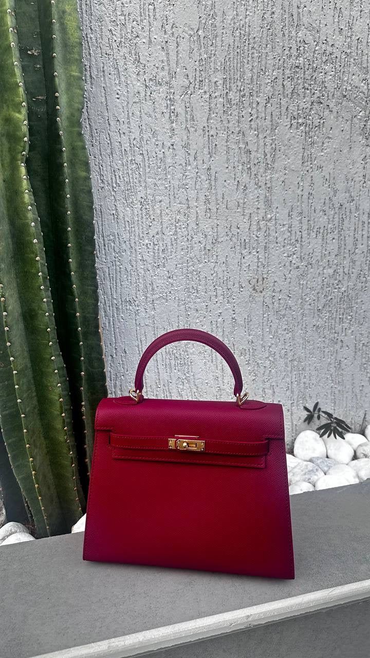 Red handbag on a stone ledge with a textured wall and cactus in the background