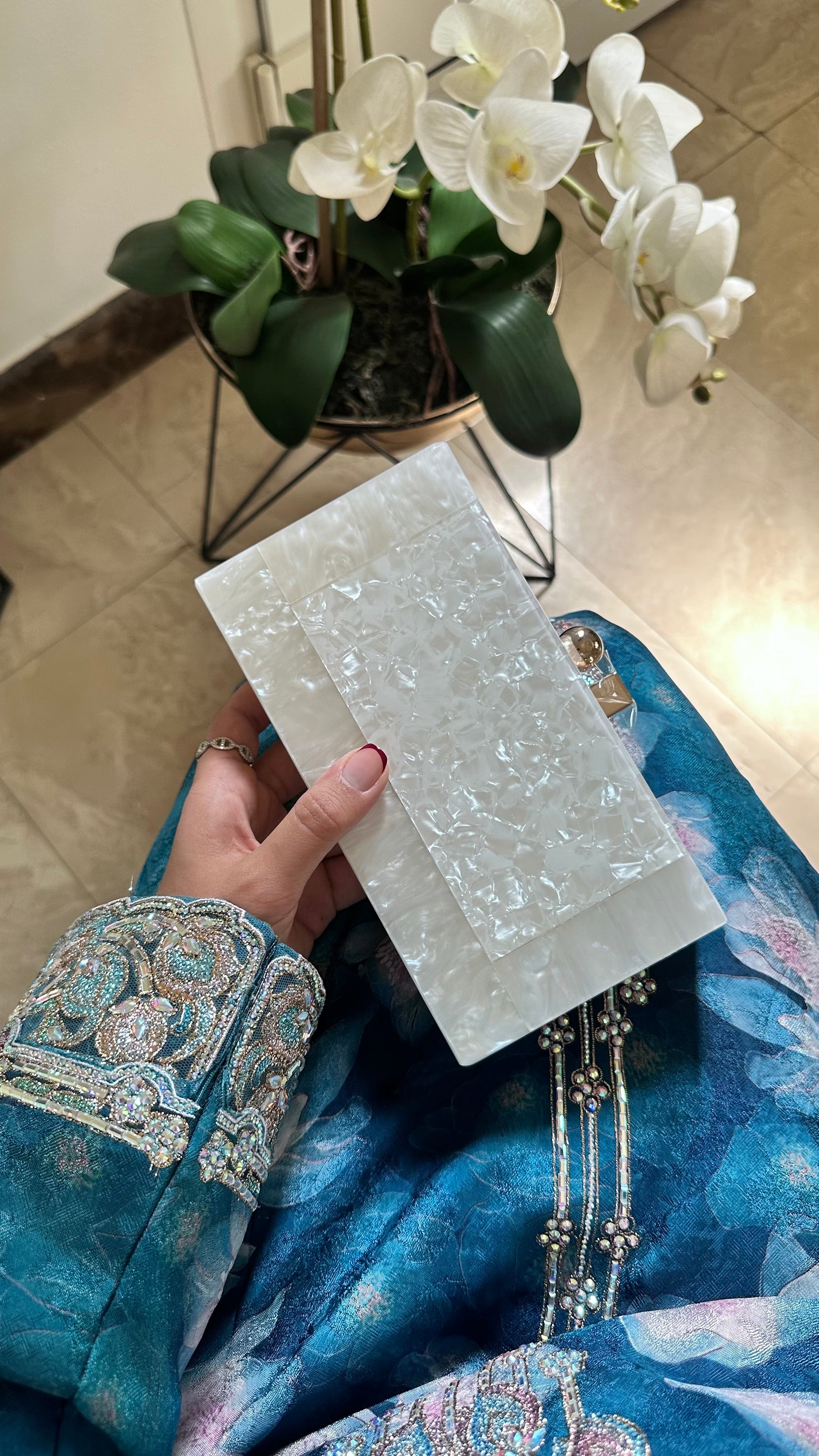 Person holding a white marble slab with floral and greenery in the background