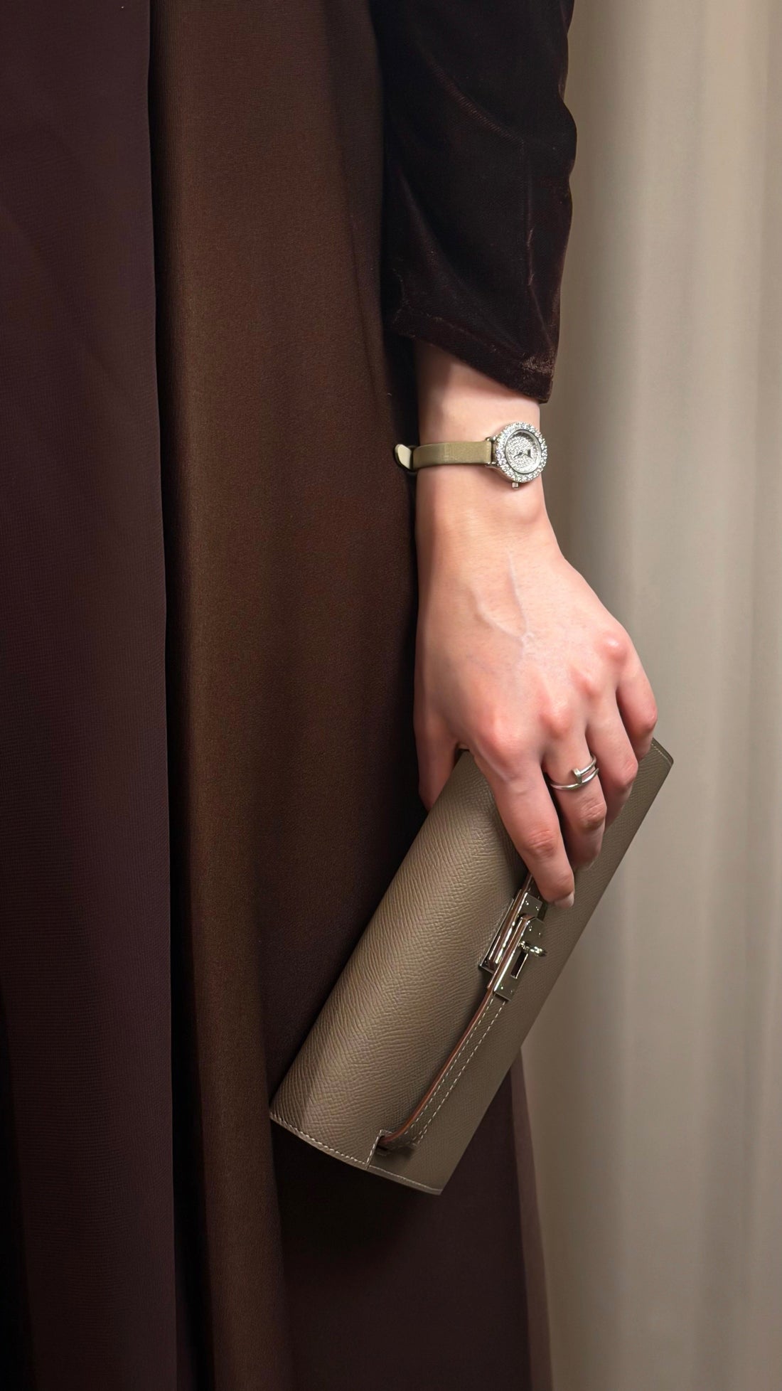 Person holding a beige clutch with a neutral background