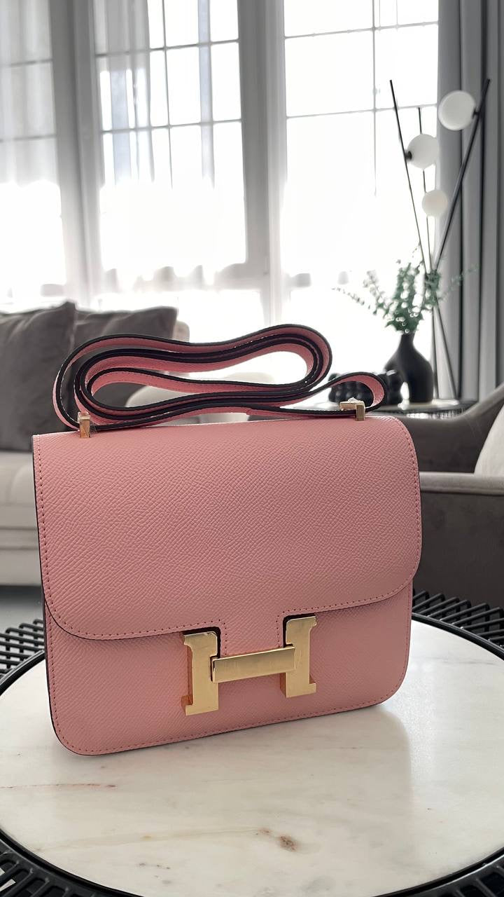 Pink handbag with gold clasp on a marble surface