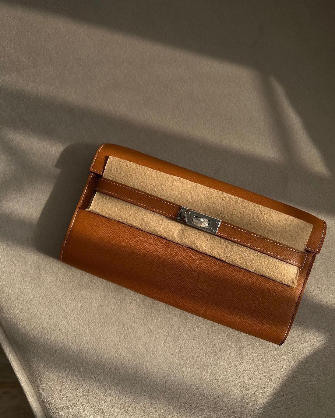 Brown leather clutch bag with beige interior on a textured surface