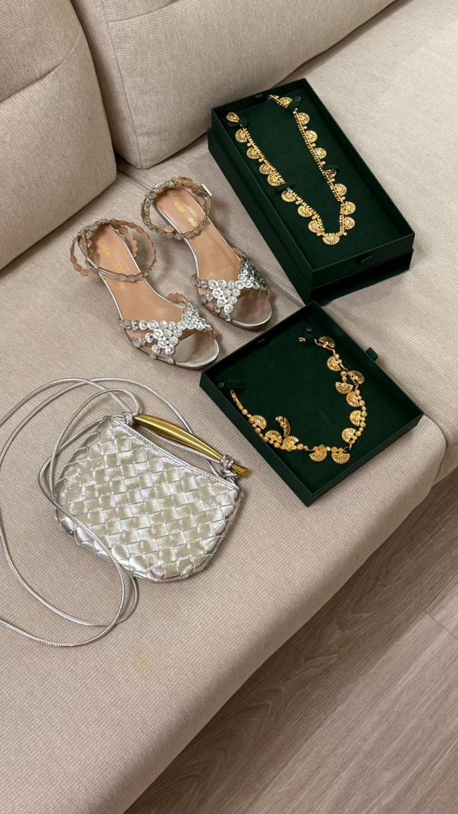 Gold jewelry and sandals on a beige surface with a neutral background