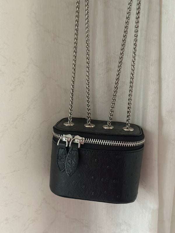 Black handbag with chain strap on a light beige background