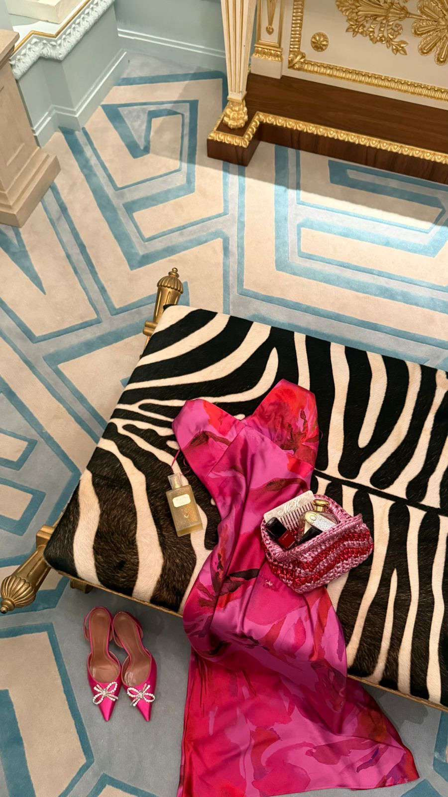 Zebra-patterned ottoman with pink fabric and shoes on a decorative floor.