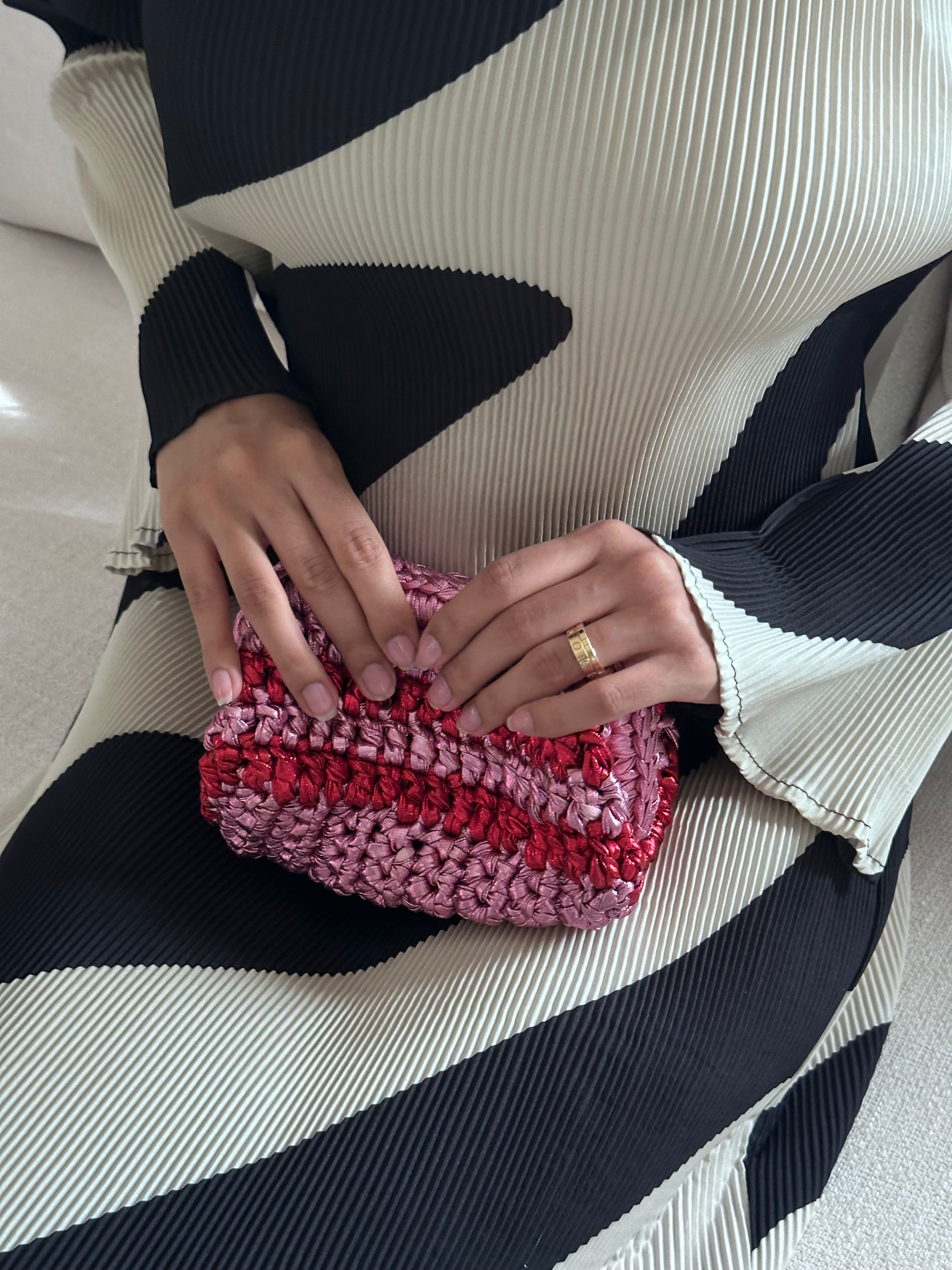 Person holding a pink crochet clutch with a striped sweater