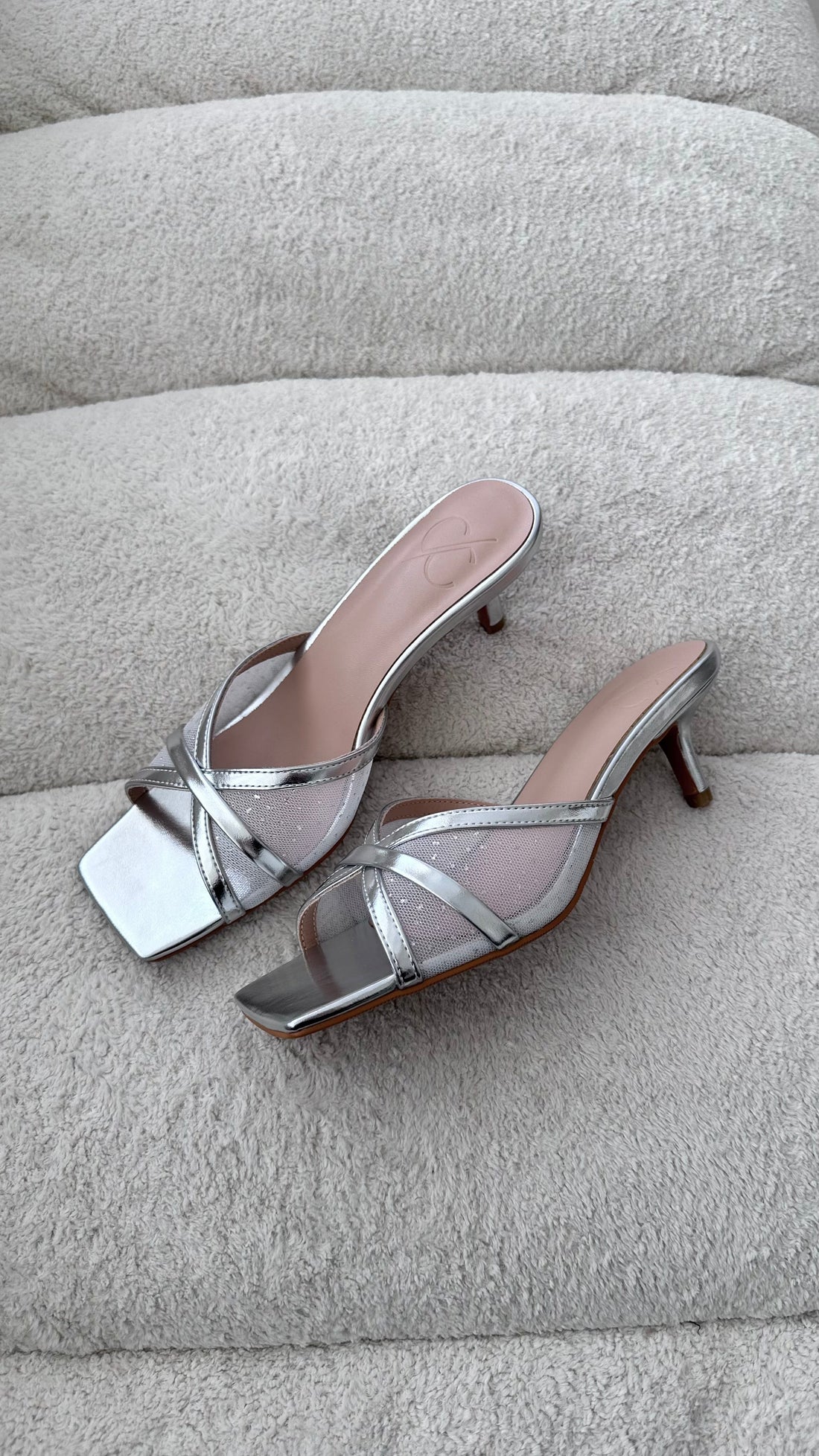 Silver high-heeled sandals on a gray textured surface
