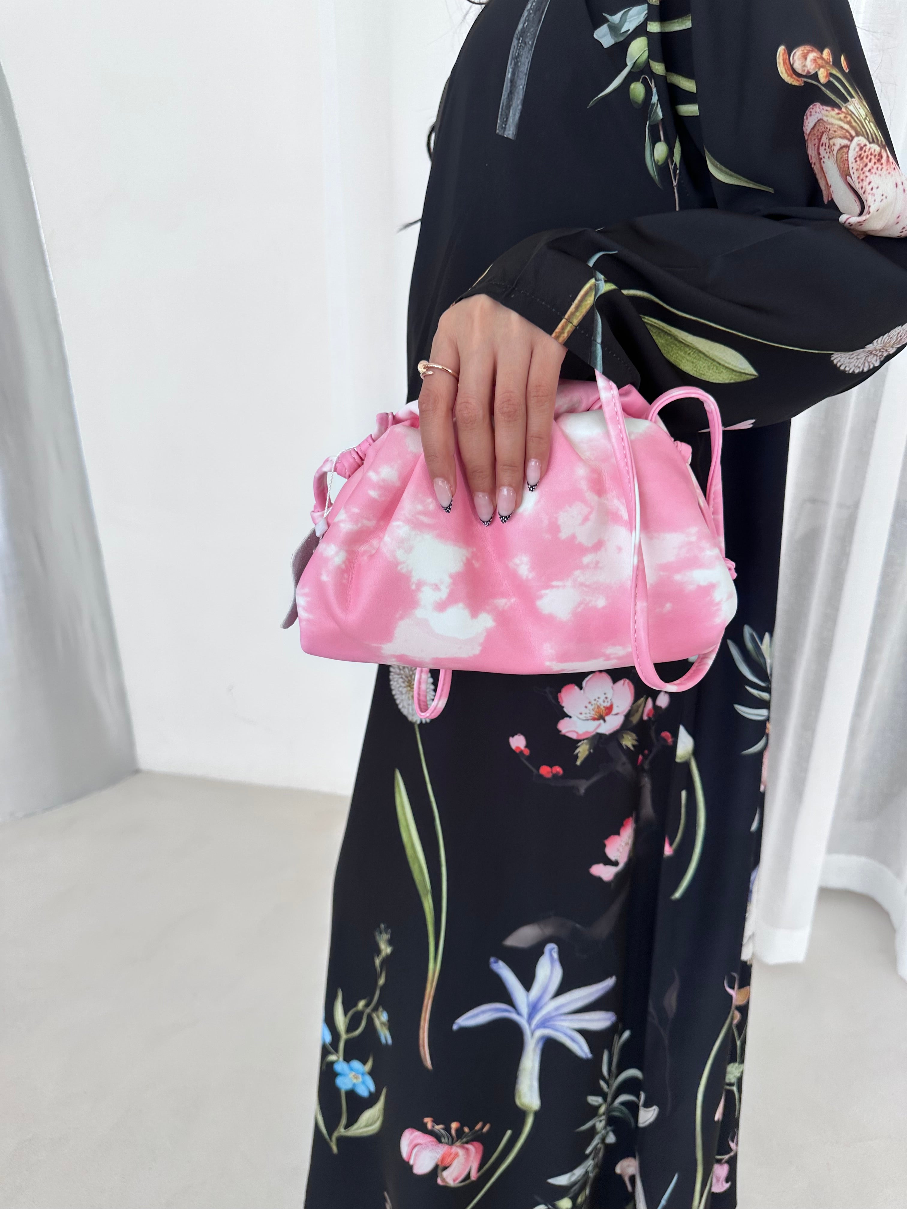 Person wearing a floral outfit holding a pink bag with a white interior.