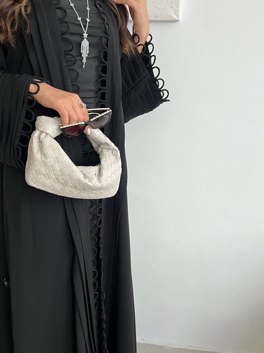 Person holding a white quilted handbag against a plain background