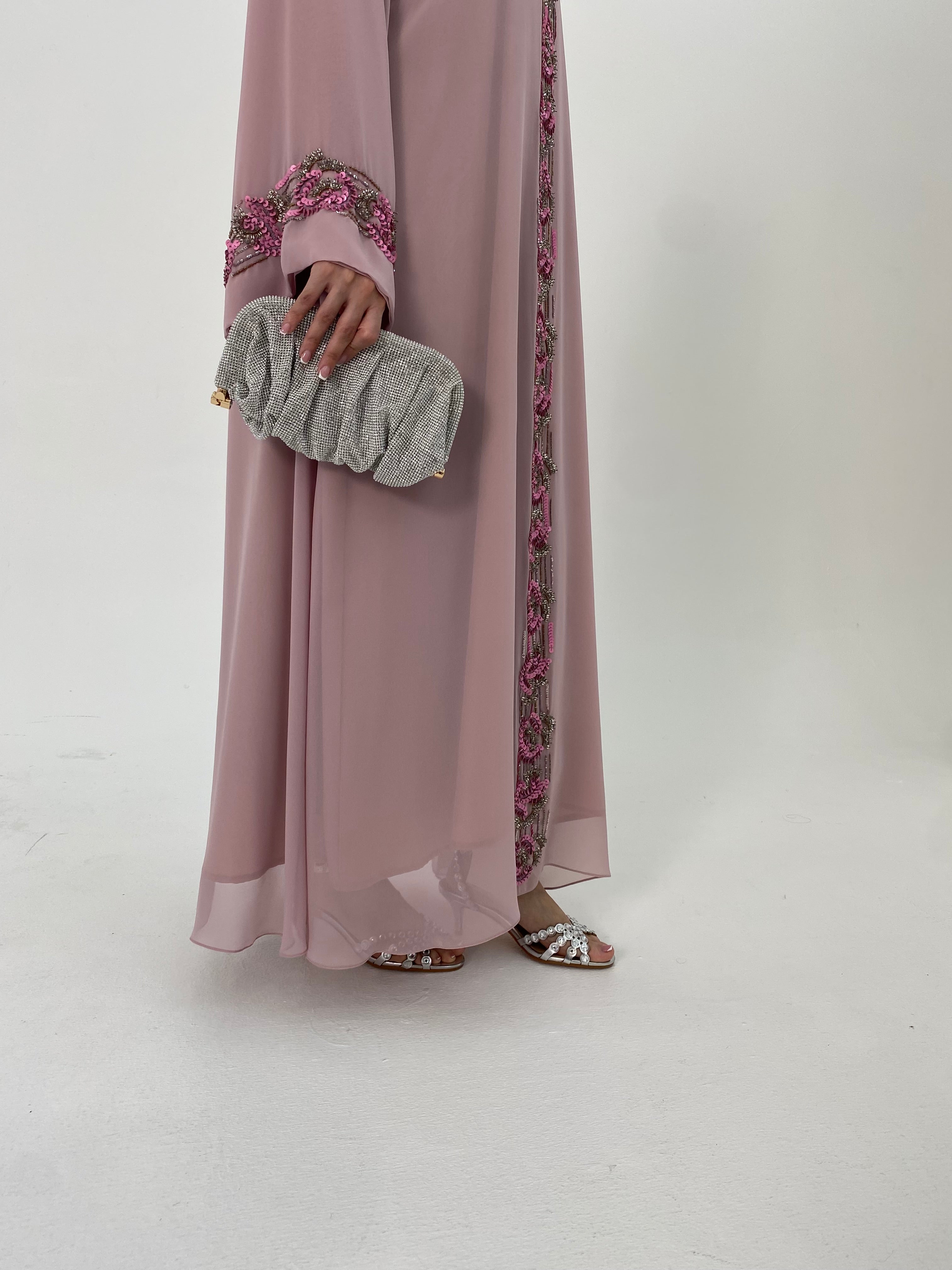 Person wearing a long pink dress with floral details on a white background