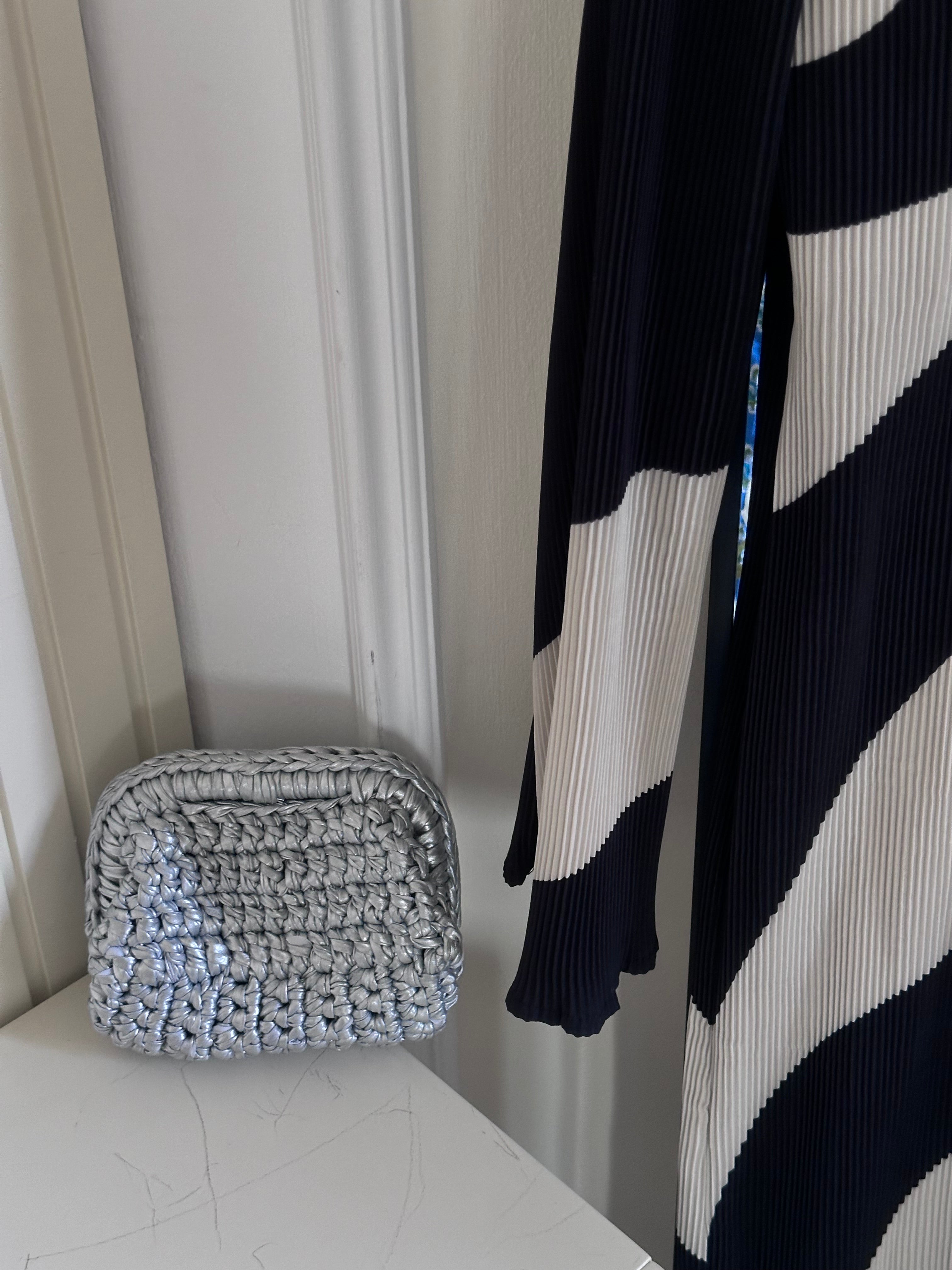 Woven basket on a white surface with a black and white striped garment in the background.