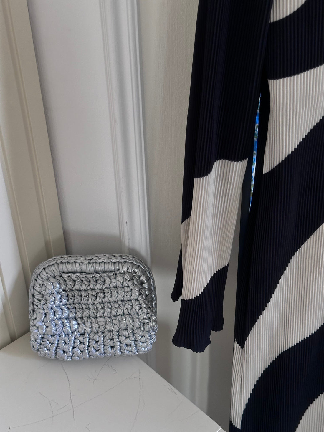 Woven basket on a white surface with a black and white striped garment in the background.