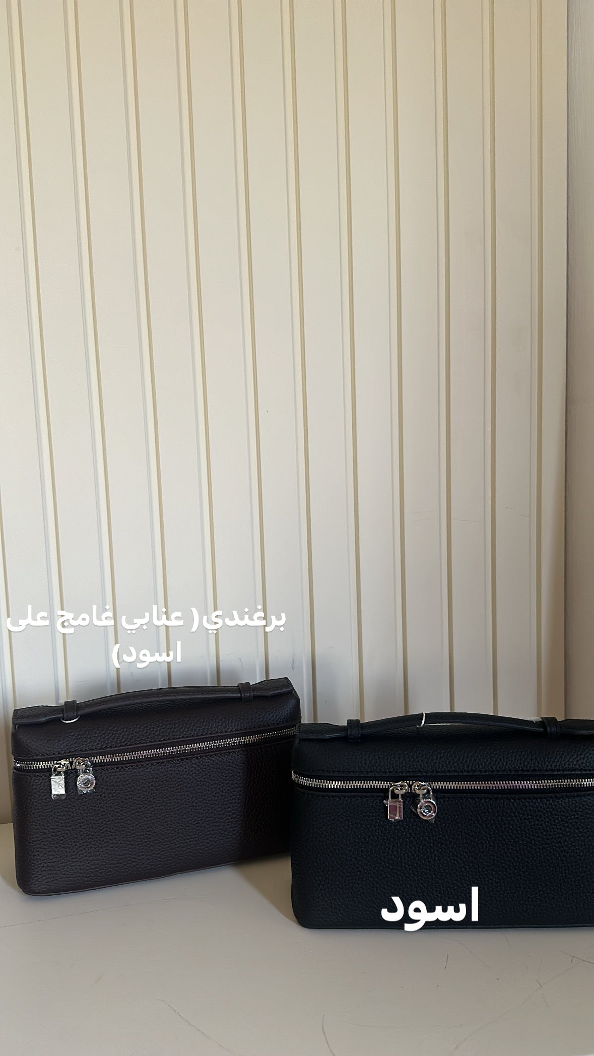 Two black bags on a light-colored floor with a striped wall background.