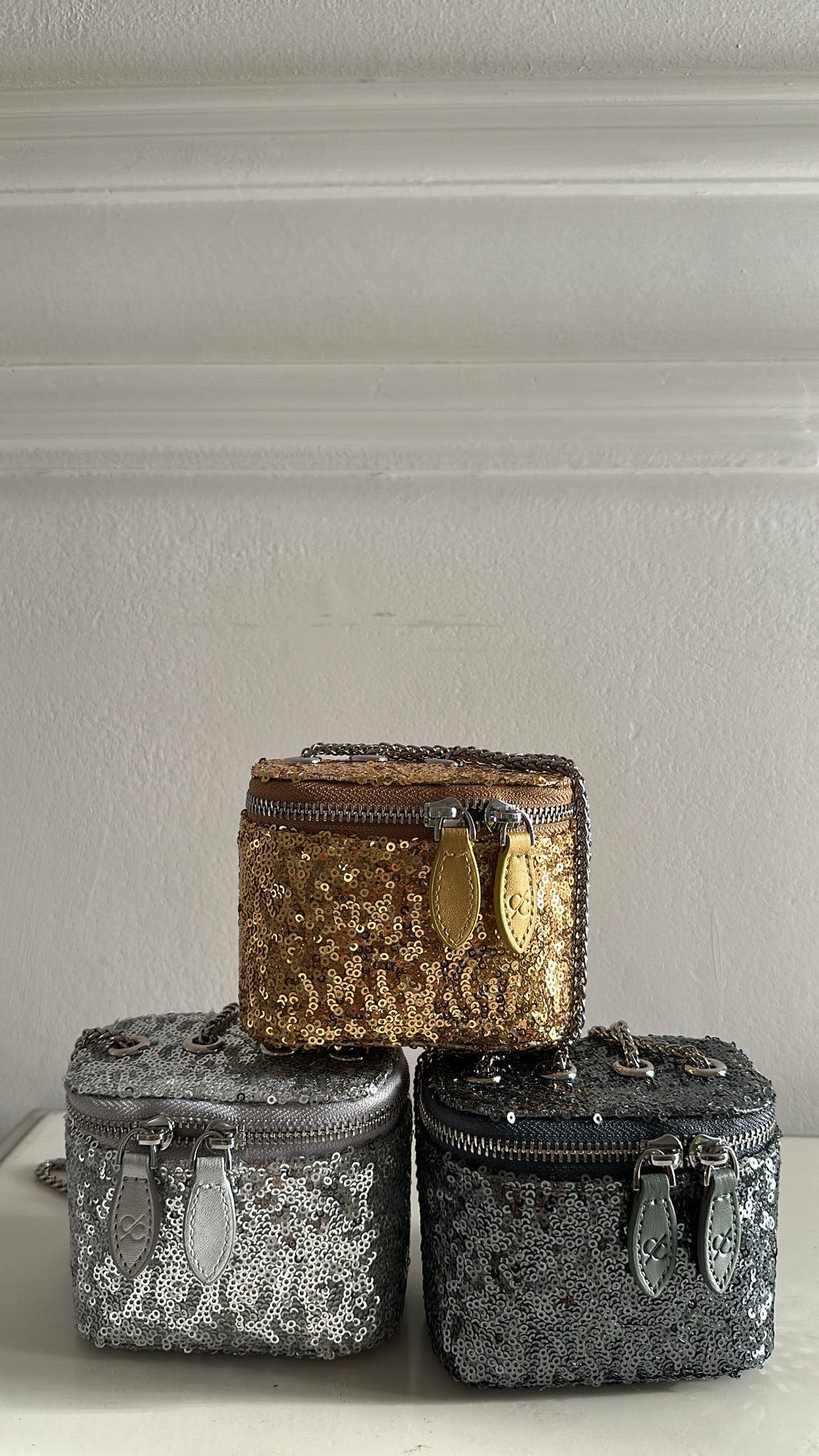Three decorative boxes with gold, silver, and black patterns on a neutral background
