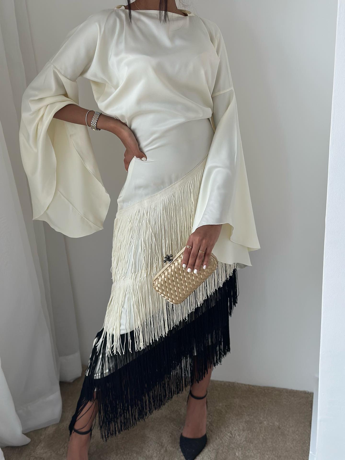 A person holding a gold clutch purse.