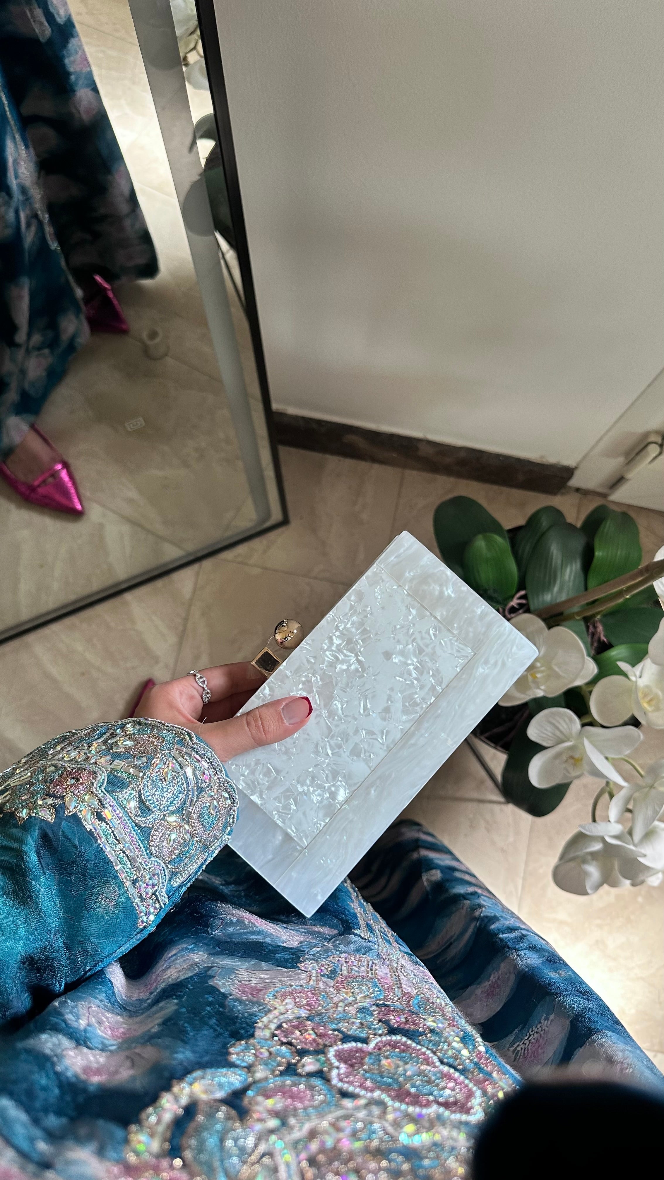 Person holding a white card with decorative patterns in front of a mirror.