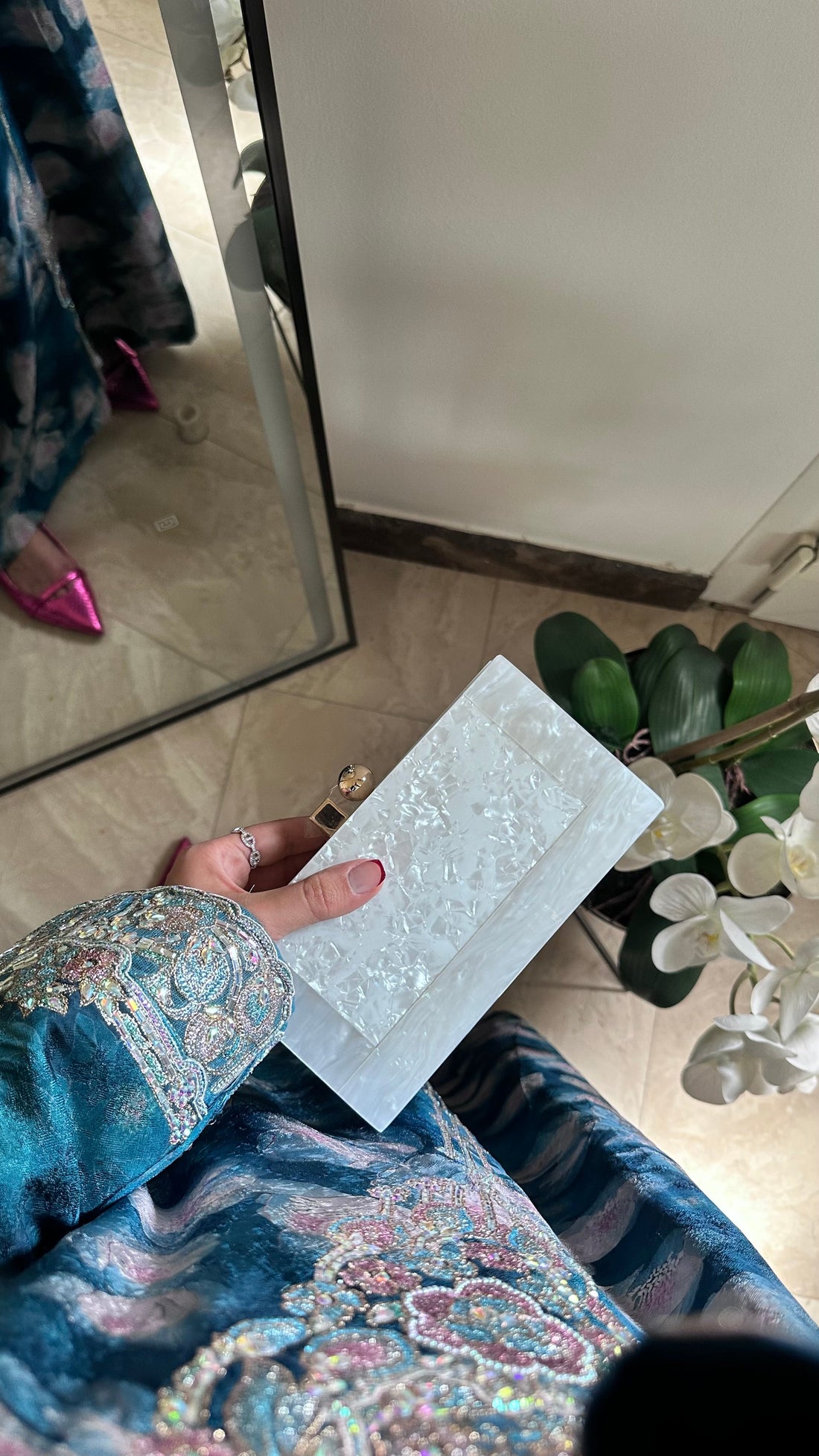 Person holding a white card with decorative patterns in front of a mirror.