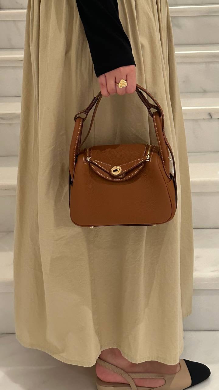 A person holding a brown leather handbag