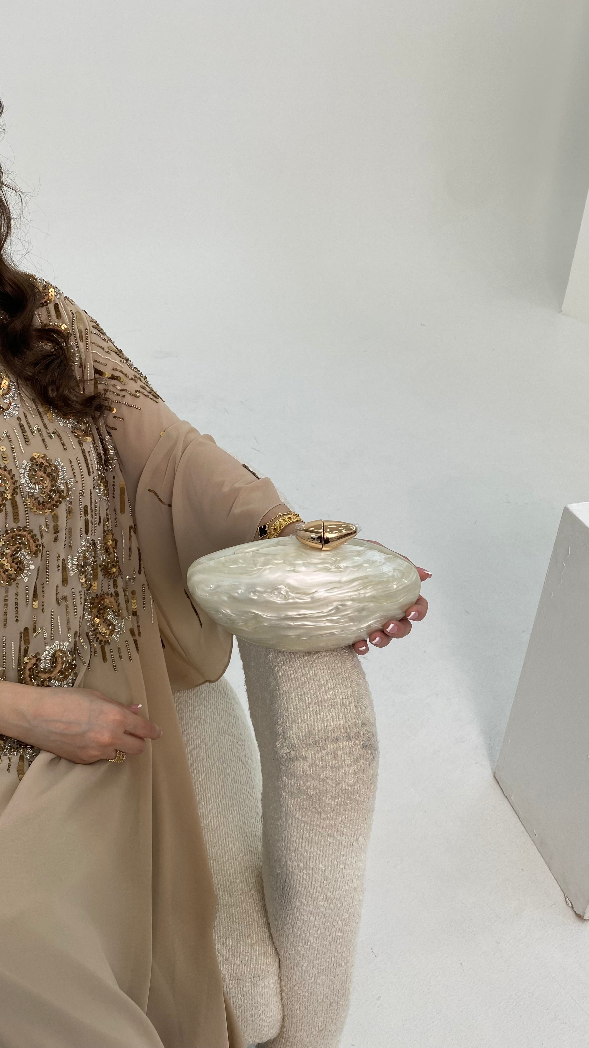 Person holding a decorative clutch against a plain background
