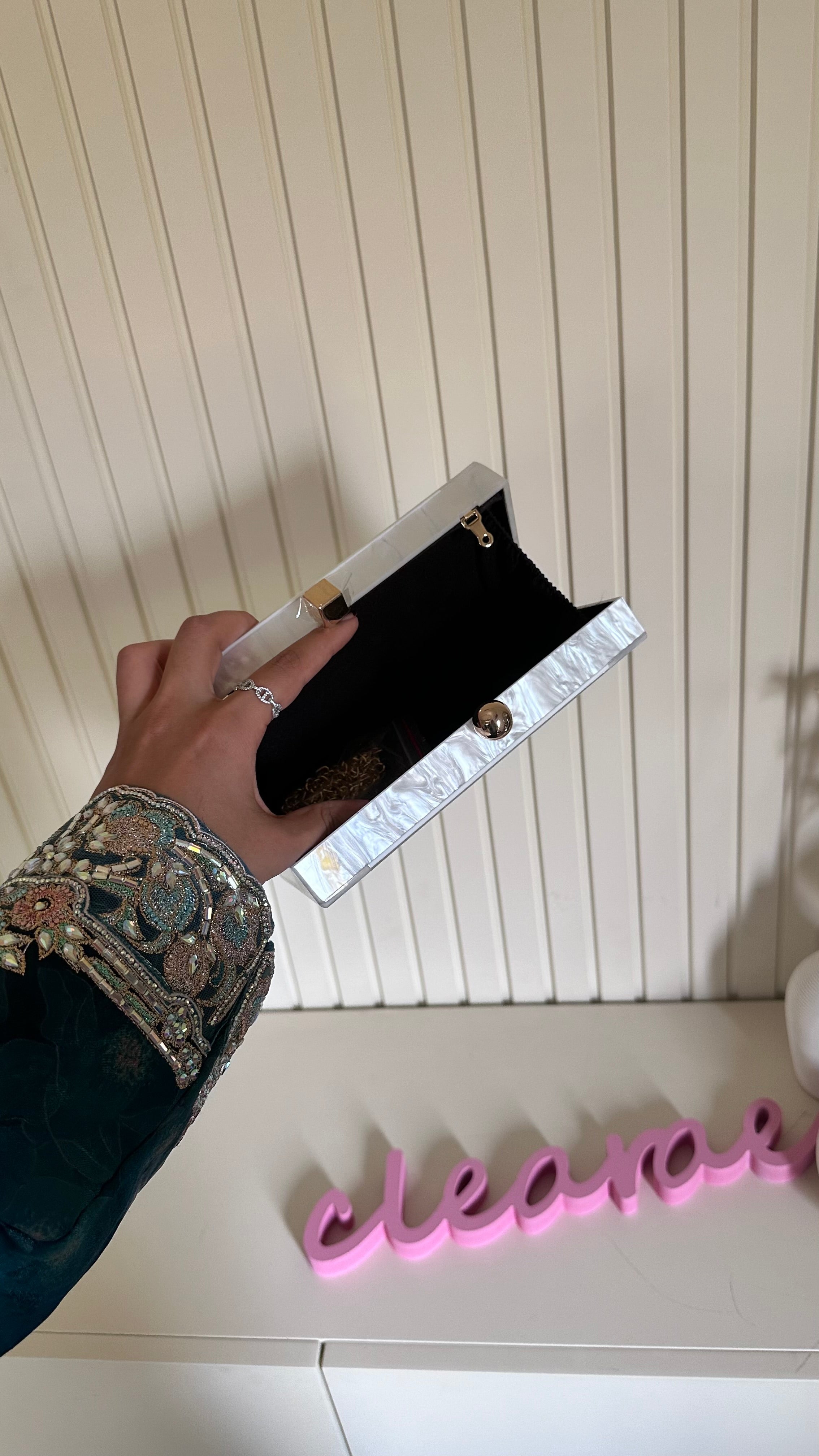 Hand holding a decorative clutch bag with a white background