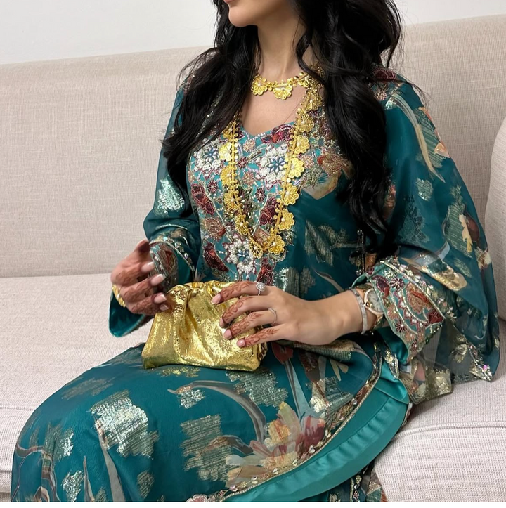 Woman in a traditional outfit holding a gold clutch on a beige couch.