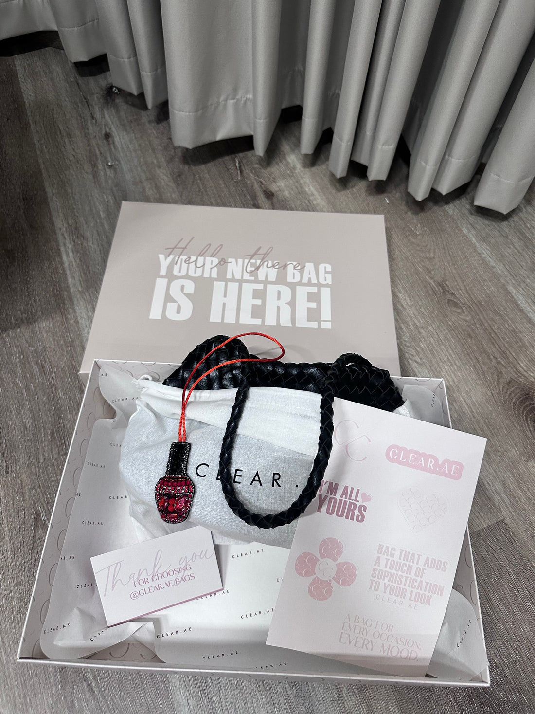 Clear plastic box with jewelry and branded paper on a wooden floor