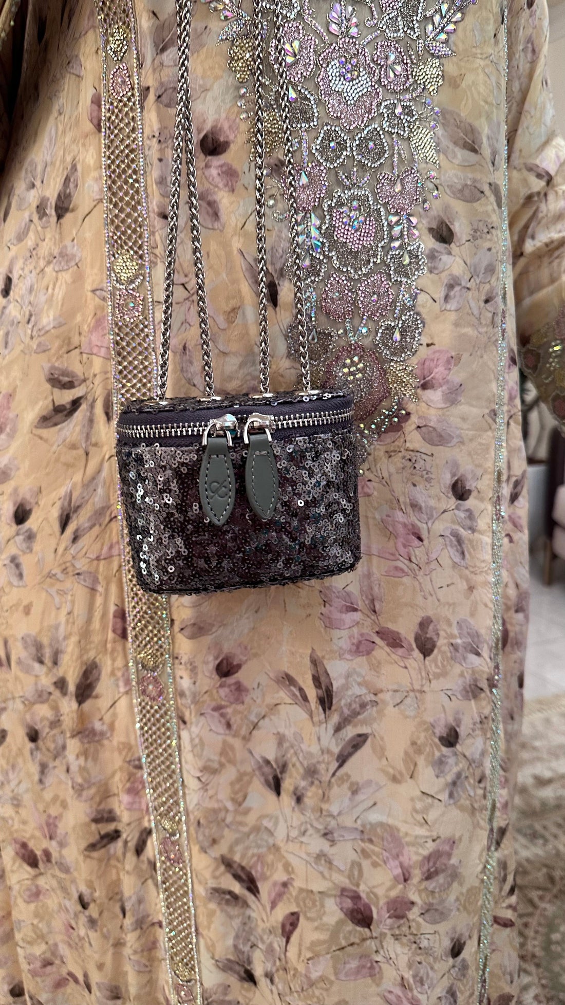Black handbag with floral embroidery on a textured fabric background