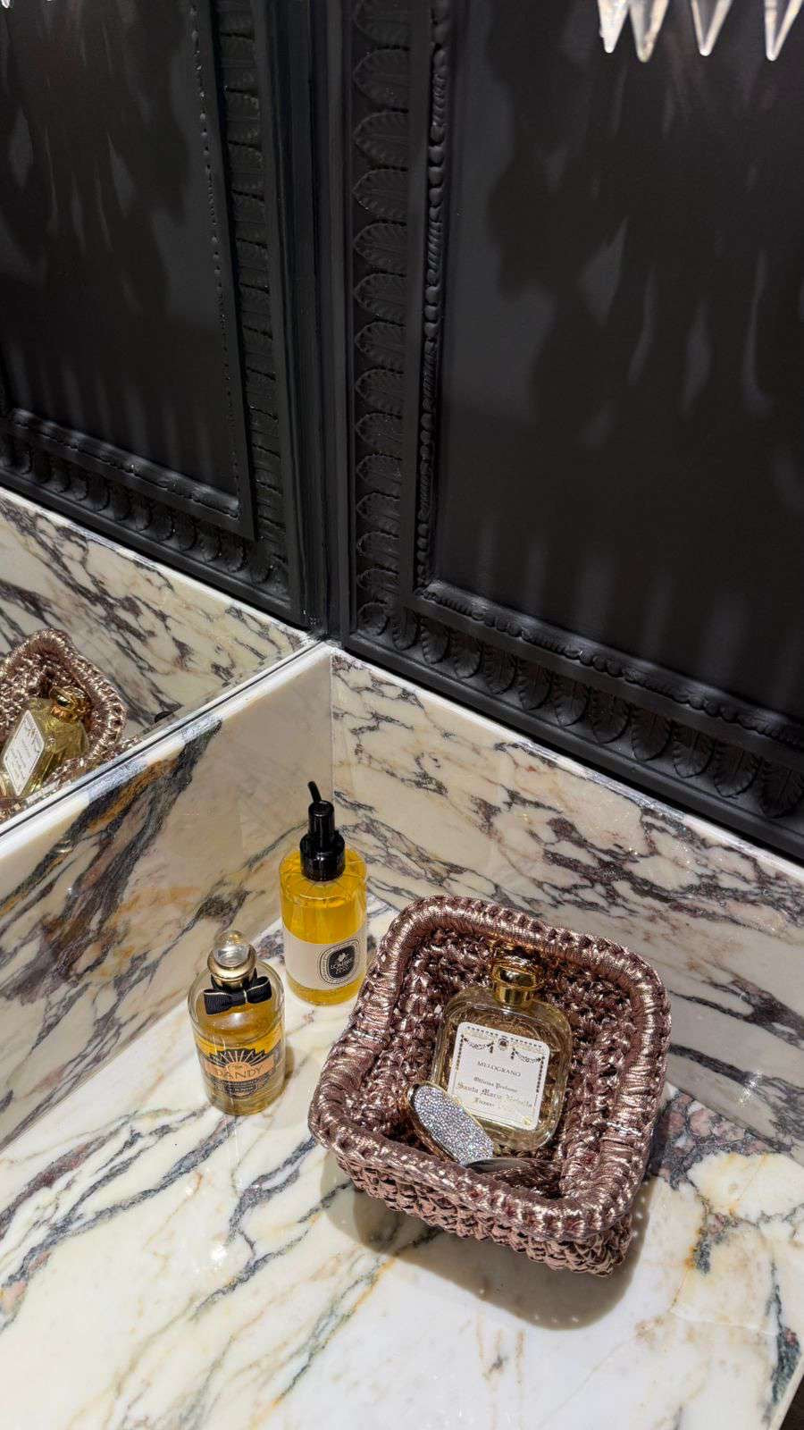 Bathroom counter with skincare products and a basket on a marble surface.