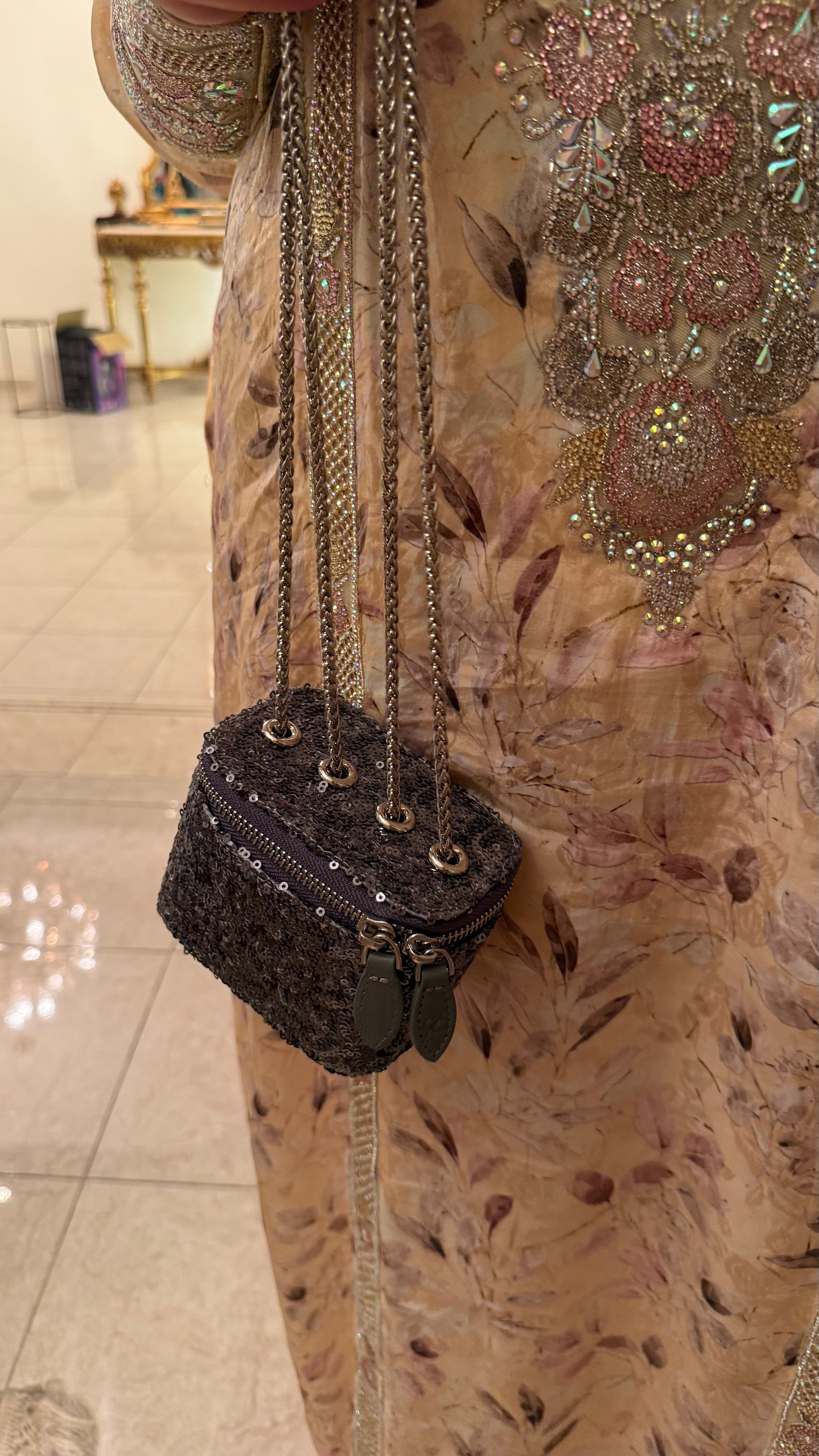 Person wearing a floral dress with a black embellished handbag